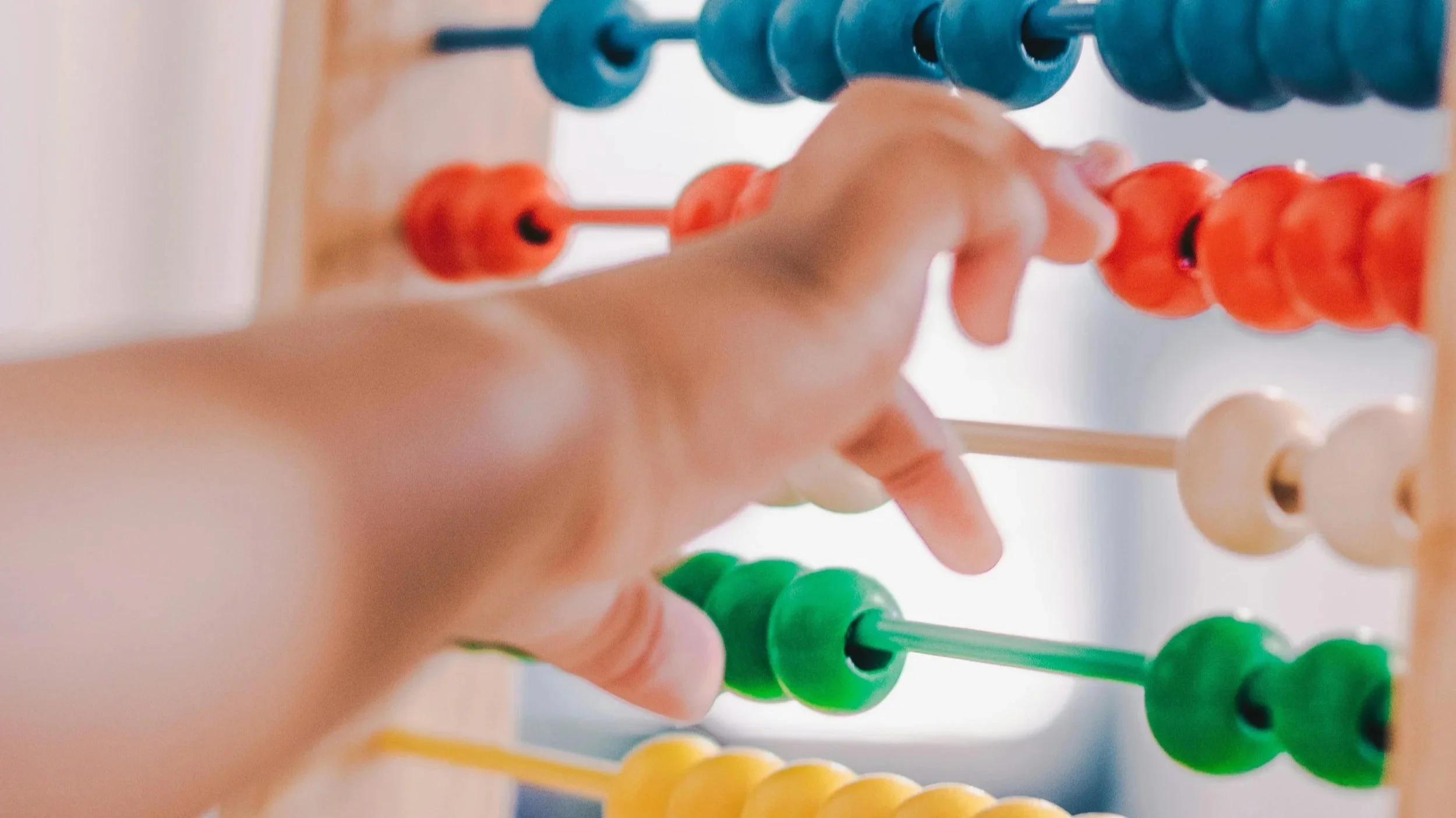 Child's hands playing with colorful wooden abacus toy