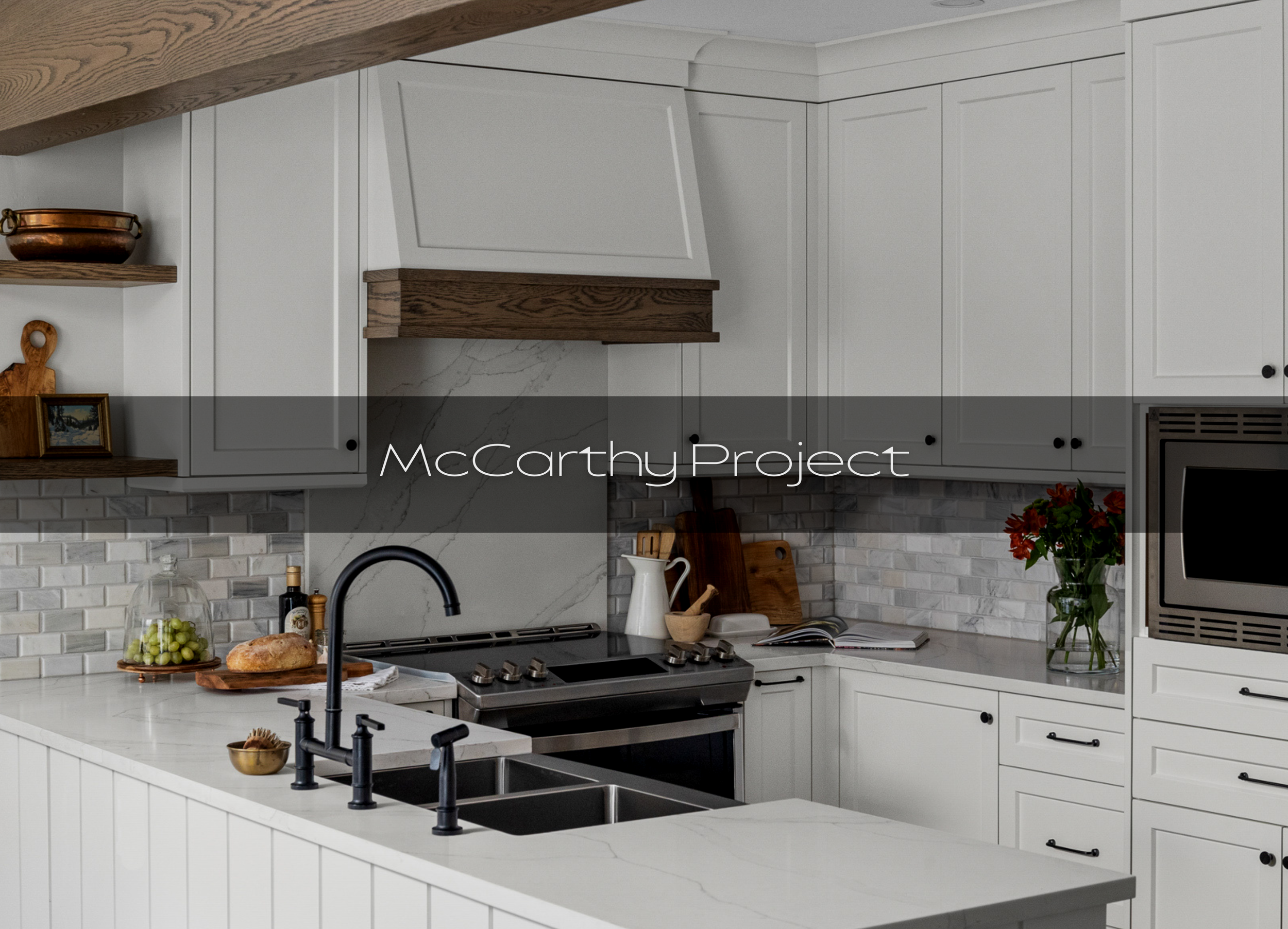Modern kitchen with white cabinets, marble backsplash, black faucet, stove, and open shelves with decorative items, a bottle of olive oil, and a loaf of bread.