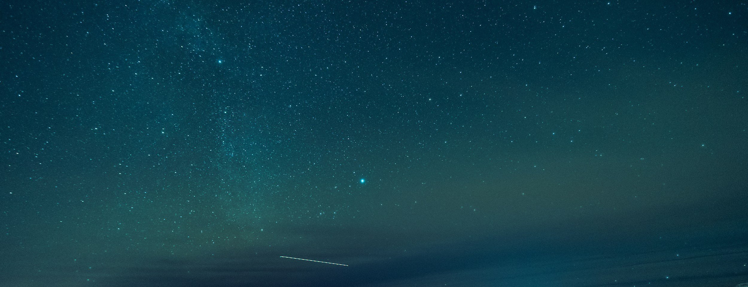 Night sky with stars and a faint meteor trail