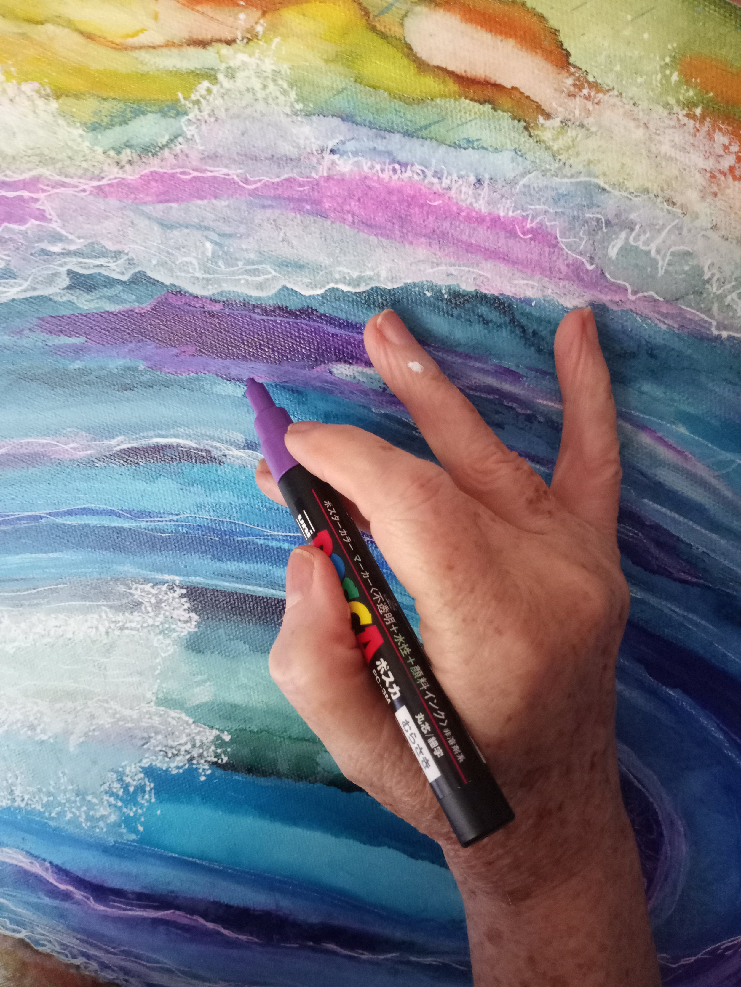 Famously Julie holding a POSCA pen, painting on an alcohol ink piece.