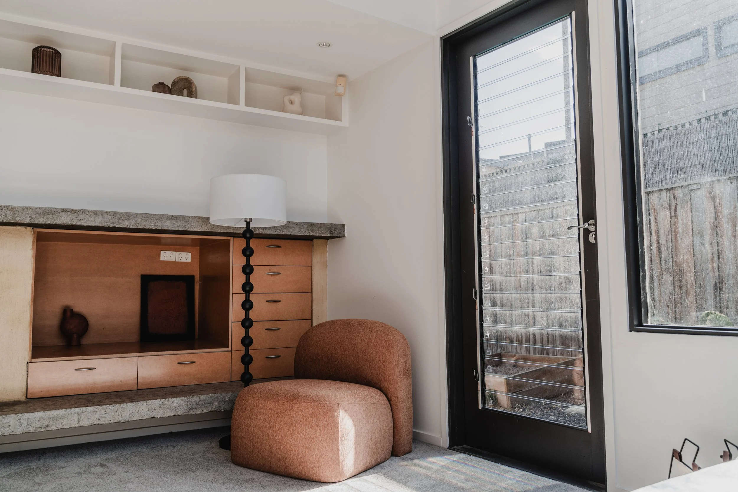 Styled Airbnb lounge with terracotta armchair and timber drawers in St Kilda cottage