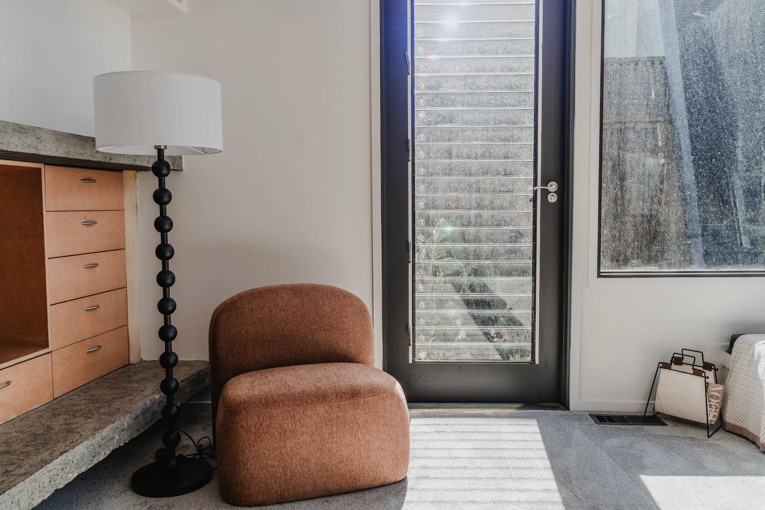 Terracotta accent chair by louvre doors in St Kilda cottage