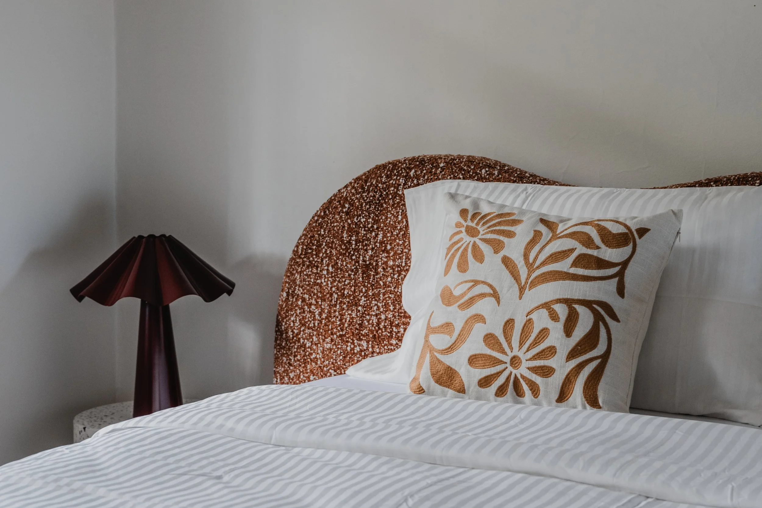 Styled bedroom with woven headboard and patterned cushion in St Kilda Airbnb