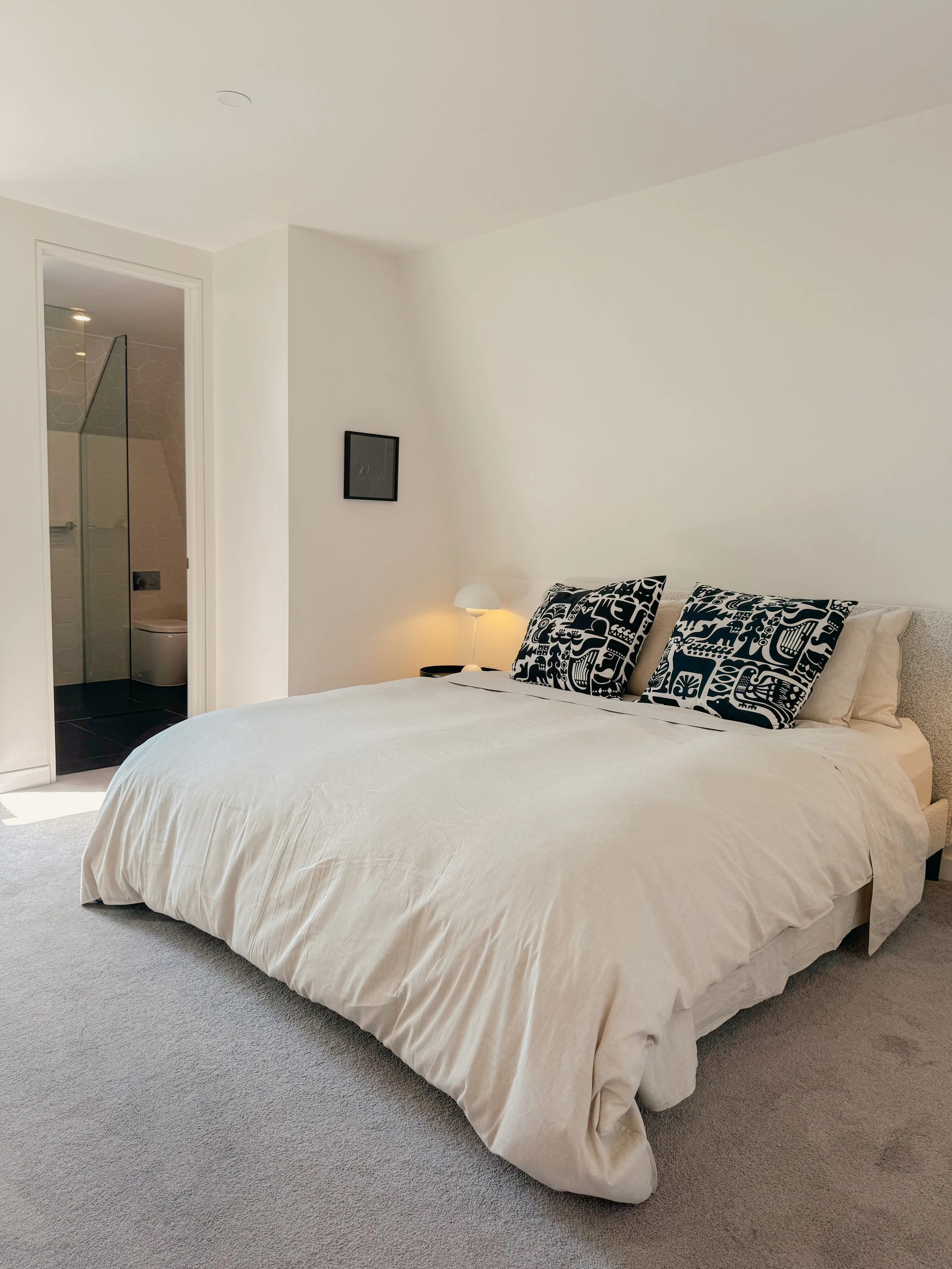 Bedroom with white linen and printed cushions in Collingwood Airbnb apartment