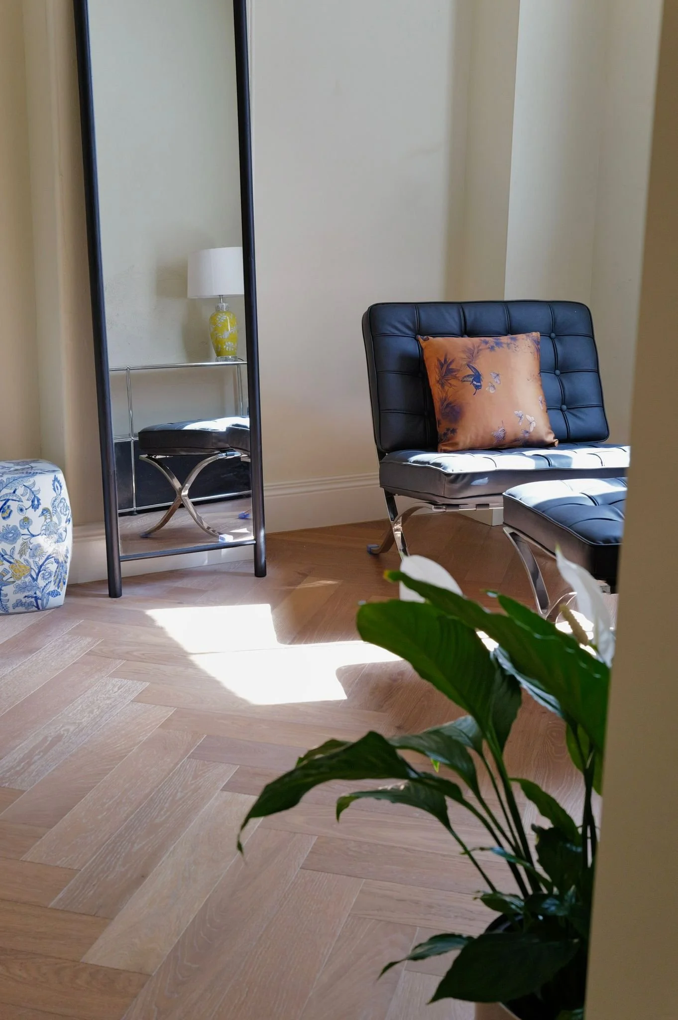 Sunlit sitting area with leather chair and plant in Fitzroy short-stay apartment