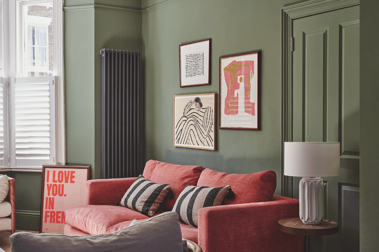 Family home is Clapham, London with green colour drenched living room and coral colour sofa