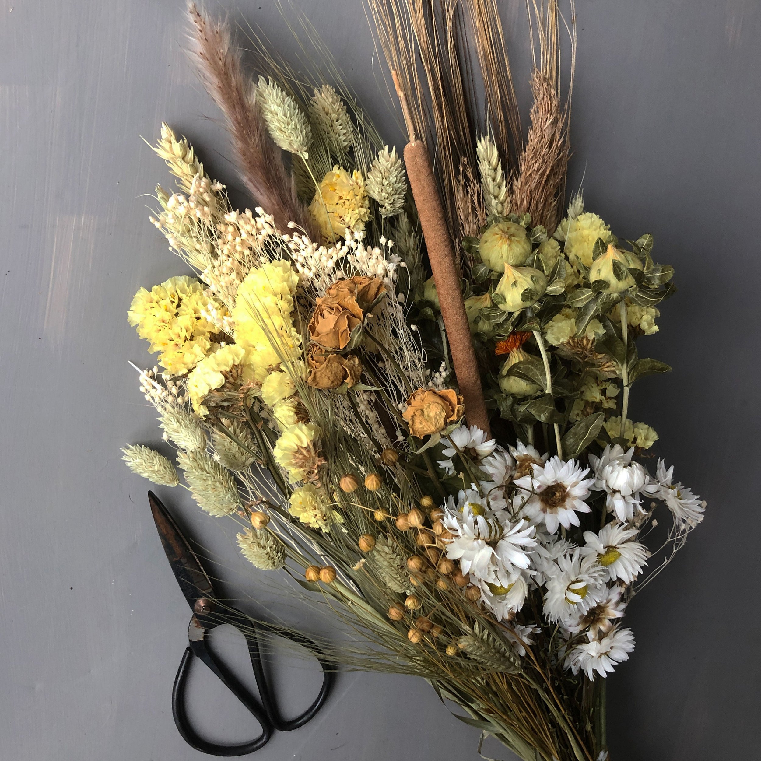 dried and floral spring sunshine bouquet on grey background with florist scissors