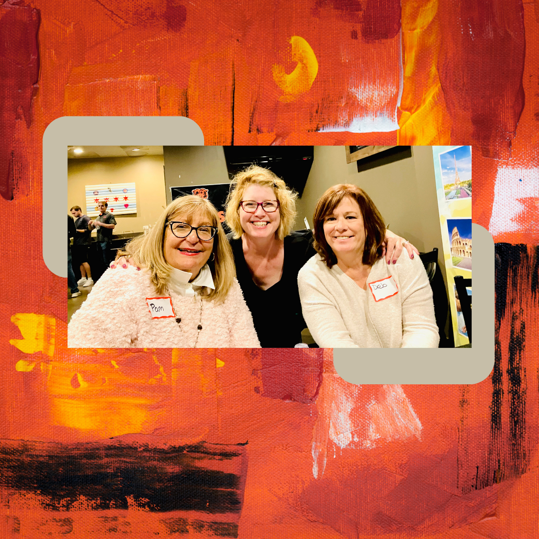 Three women smiling at a social gathering, two wearing name tags that read 'Pam' and 'Joe'