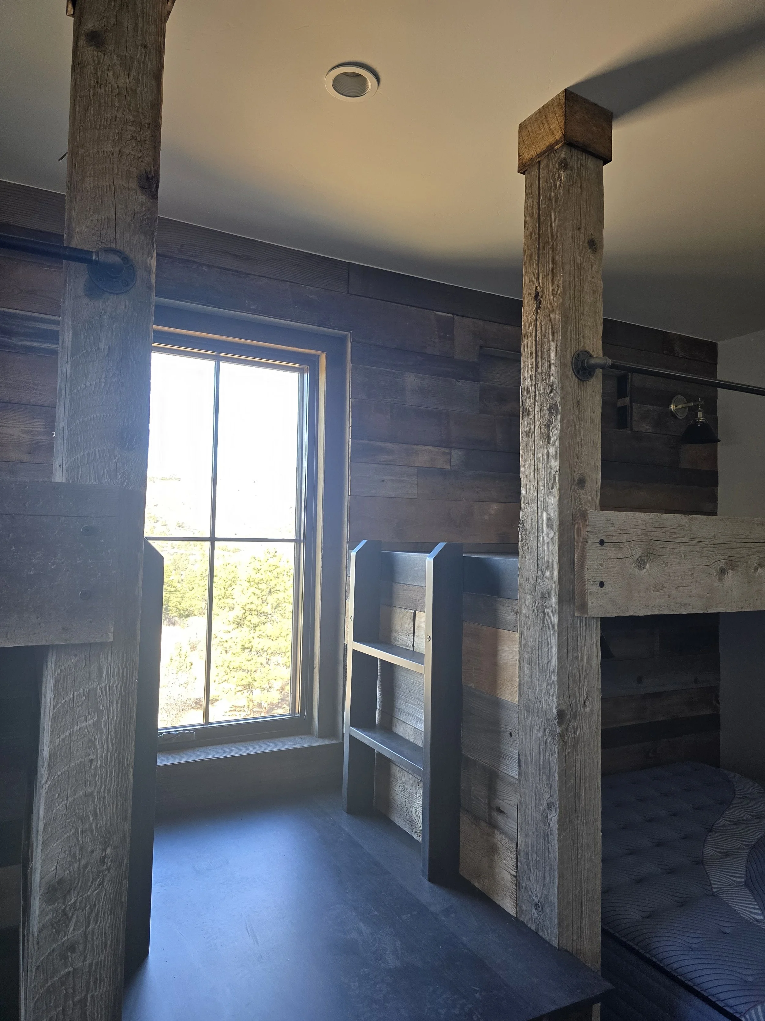 Detail of custom reclaimed wood bunk bed with built-in stairs to platform and short ladders to top bunks—durable, functional design by Animas Craft Woodworks.