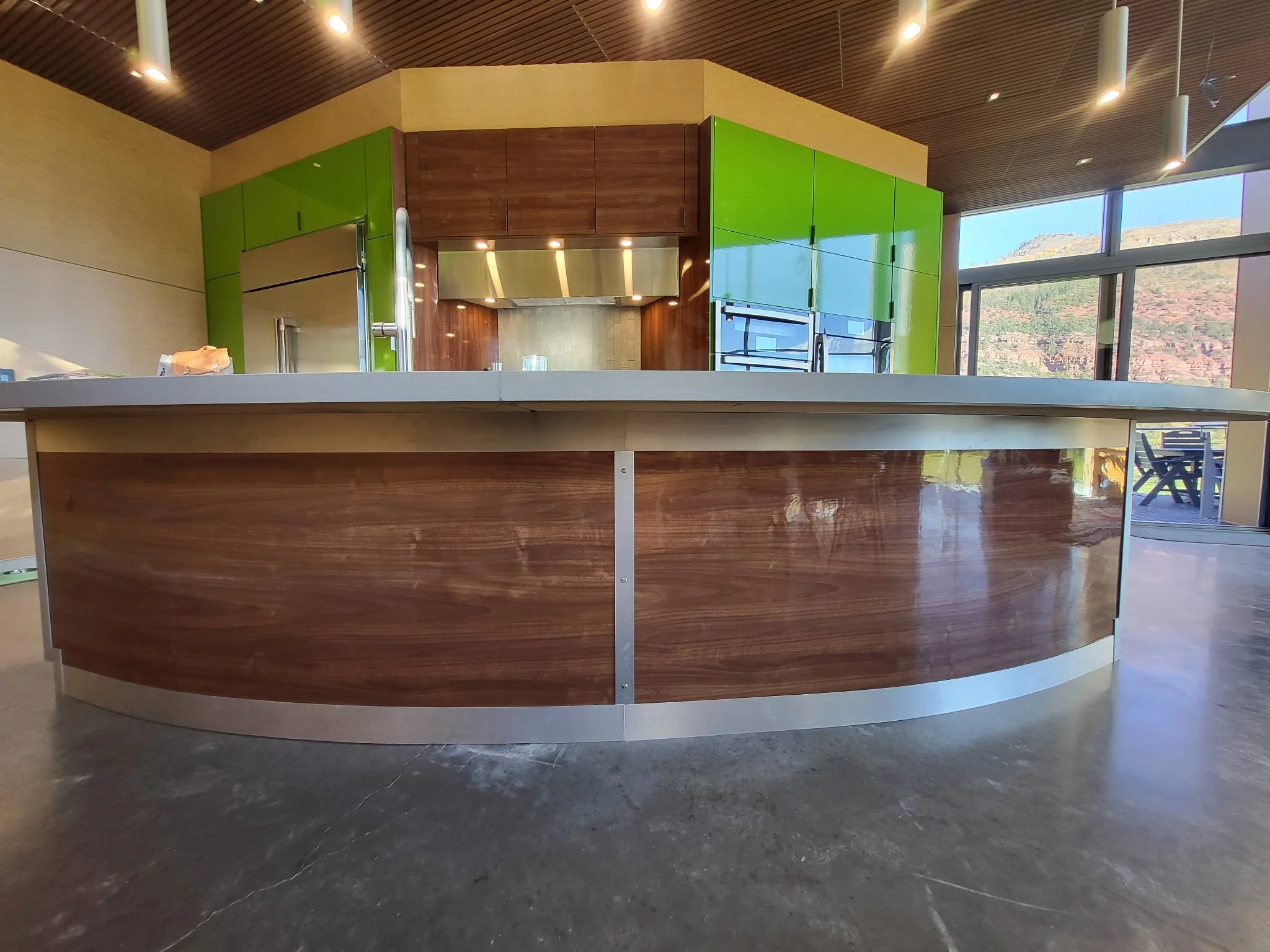 Back of curved kitchen island featuring custom-layup gloss walnut veneer and aluminum edging—ultra-modern detail in ACW contemporary kitchen project.