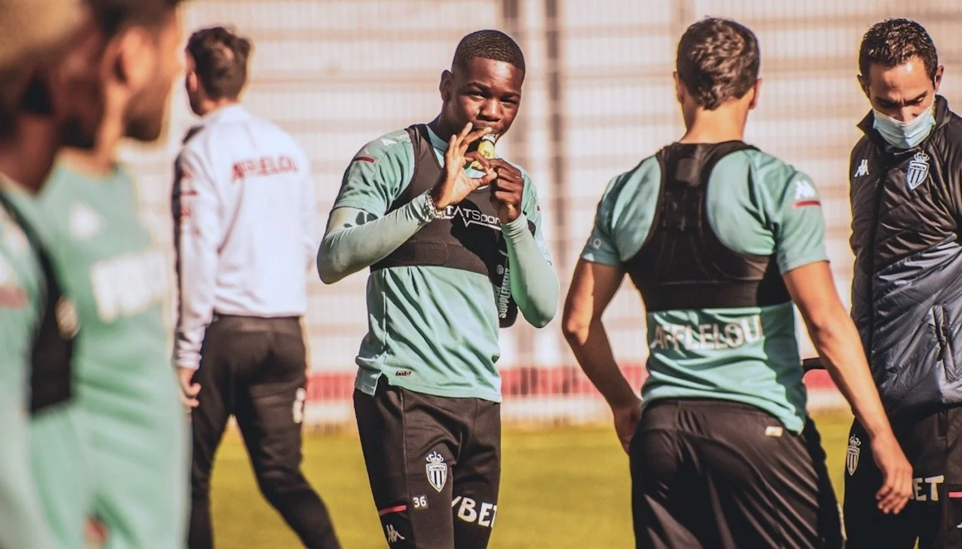 Soccer players on the field during practice, with one player eating an energy bar.