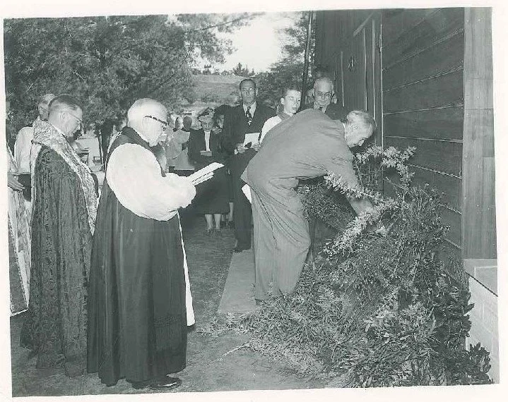 Historic black-and-white photograph of the 1950 dedication of All Saints' Episcopal Church in Vista, California, with clergy and parishioners gathered outside the church.