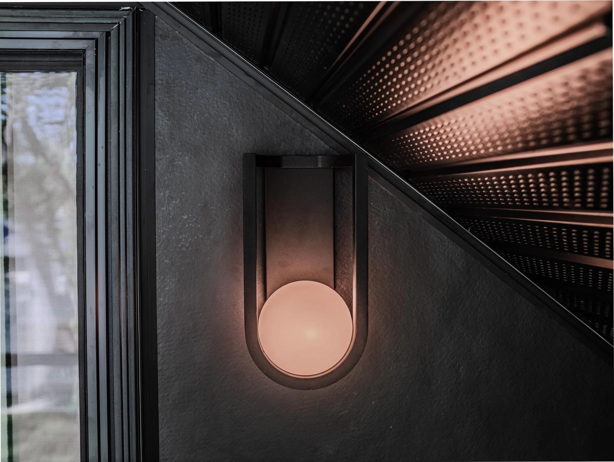 Modern globe wall sconce lighting against a dark textured accent wall in a bespoke residential build.