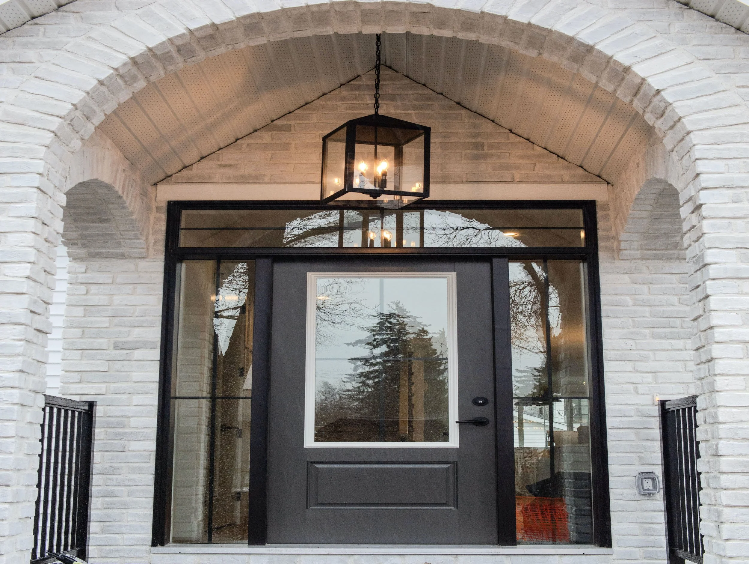 Architectural white brick archway framing the glass-encased transom front entrance of The Westmount Artisan.