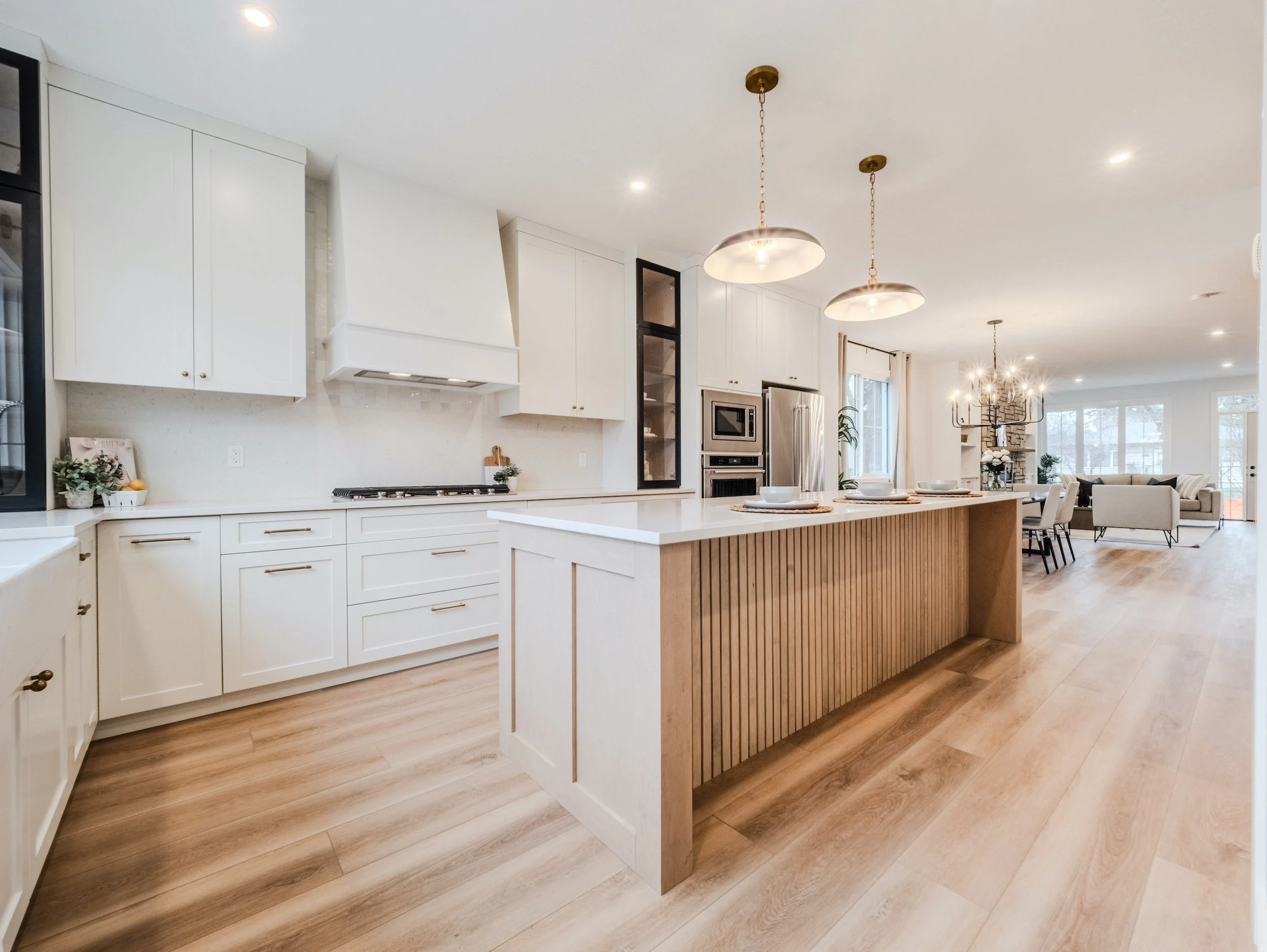 Modern kitchen featuring a fluted wood island, quartz waterfall counters, and farmhouse sink.