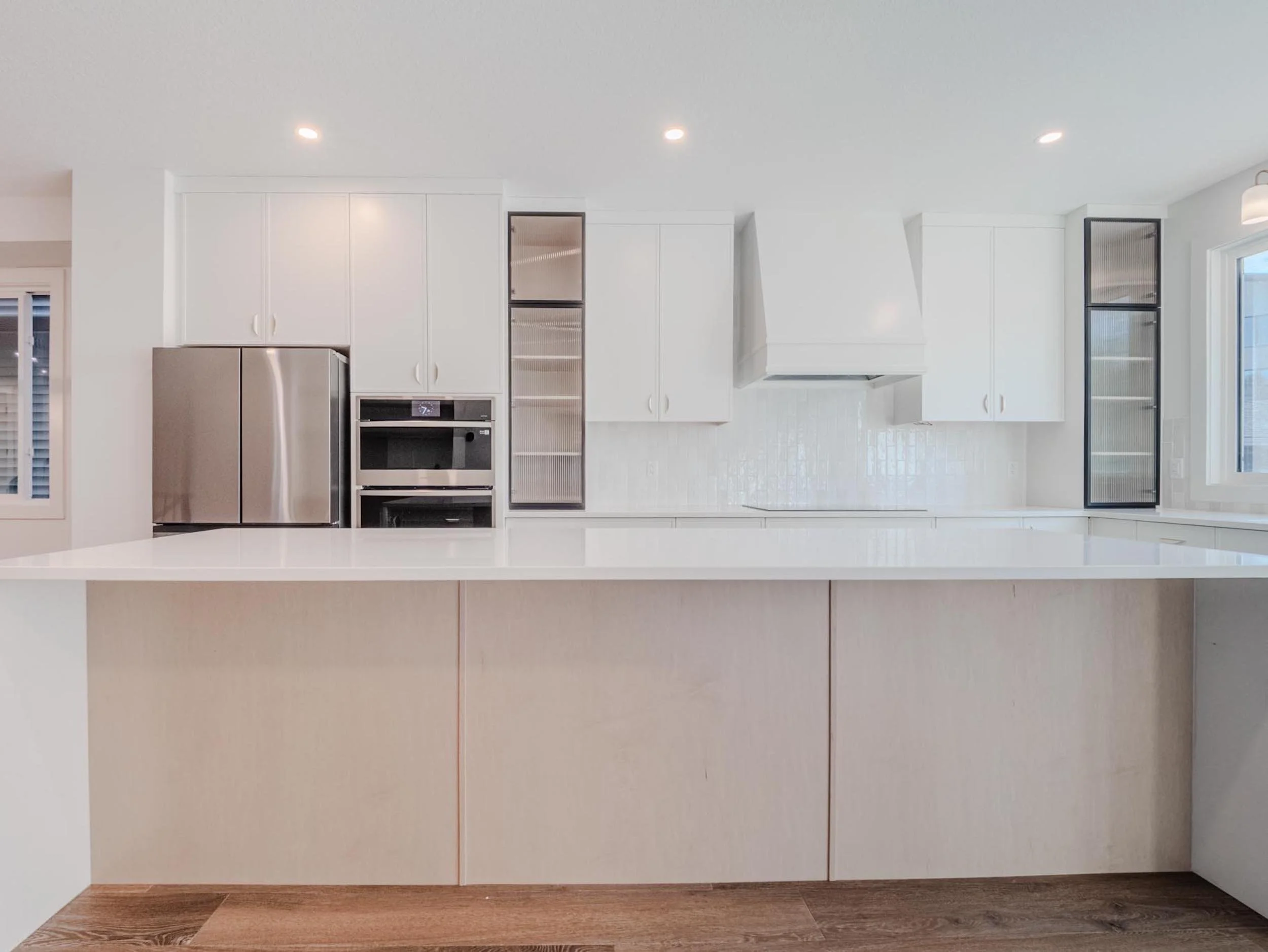 Modern white kitchen with custom cabinetry and built-in appliances in a luxury Edmonton custom home.
