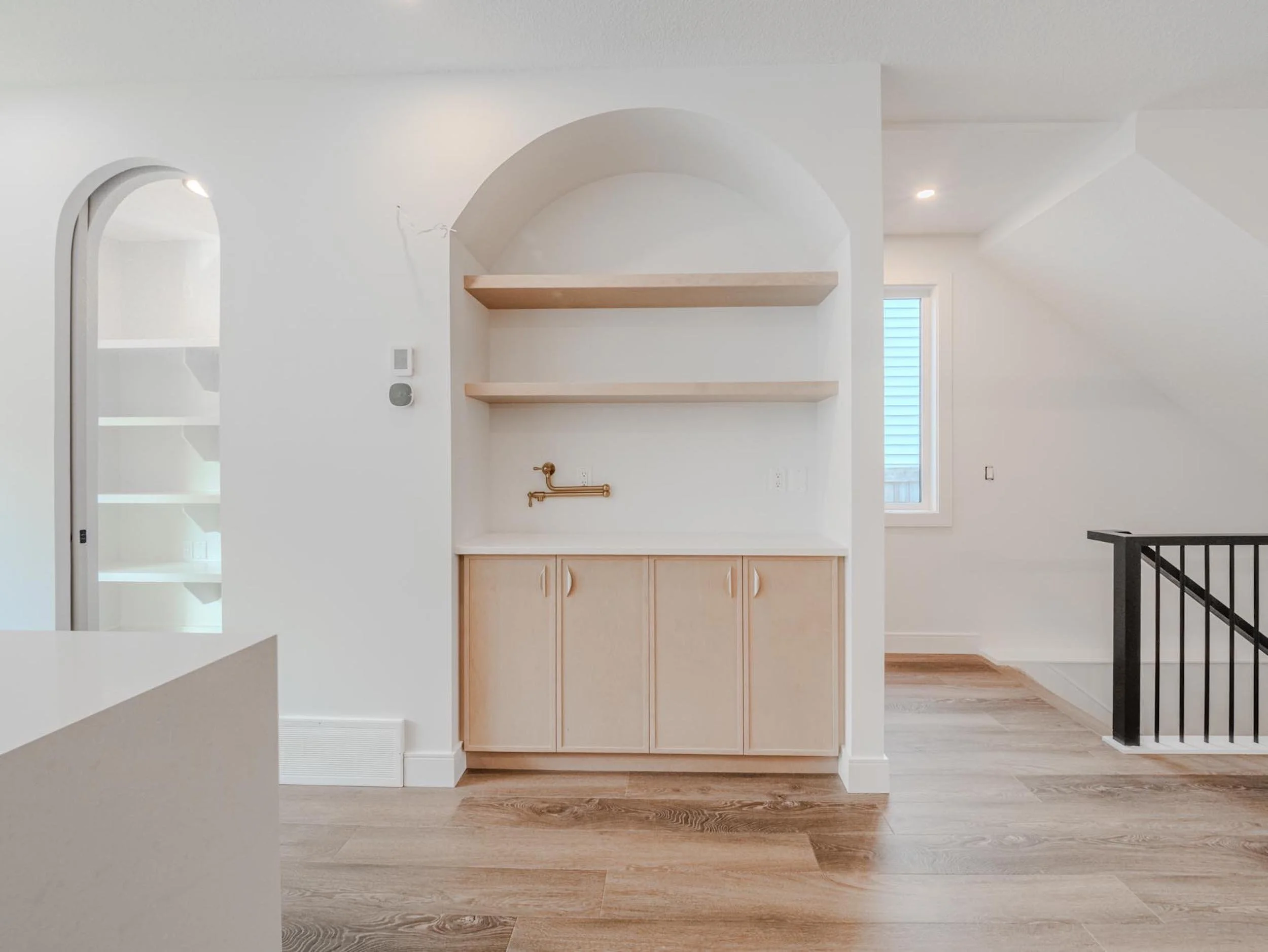 Custom arched coffee station with integrated pot filler in a luxury Edmonton infill kitchen.
