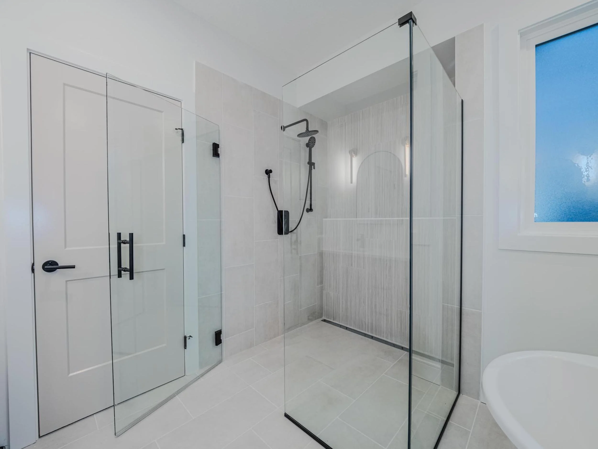 Modern spa ensuite featuring a curbless shower with floor-to-ceiling tile in an Edmonton infill.