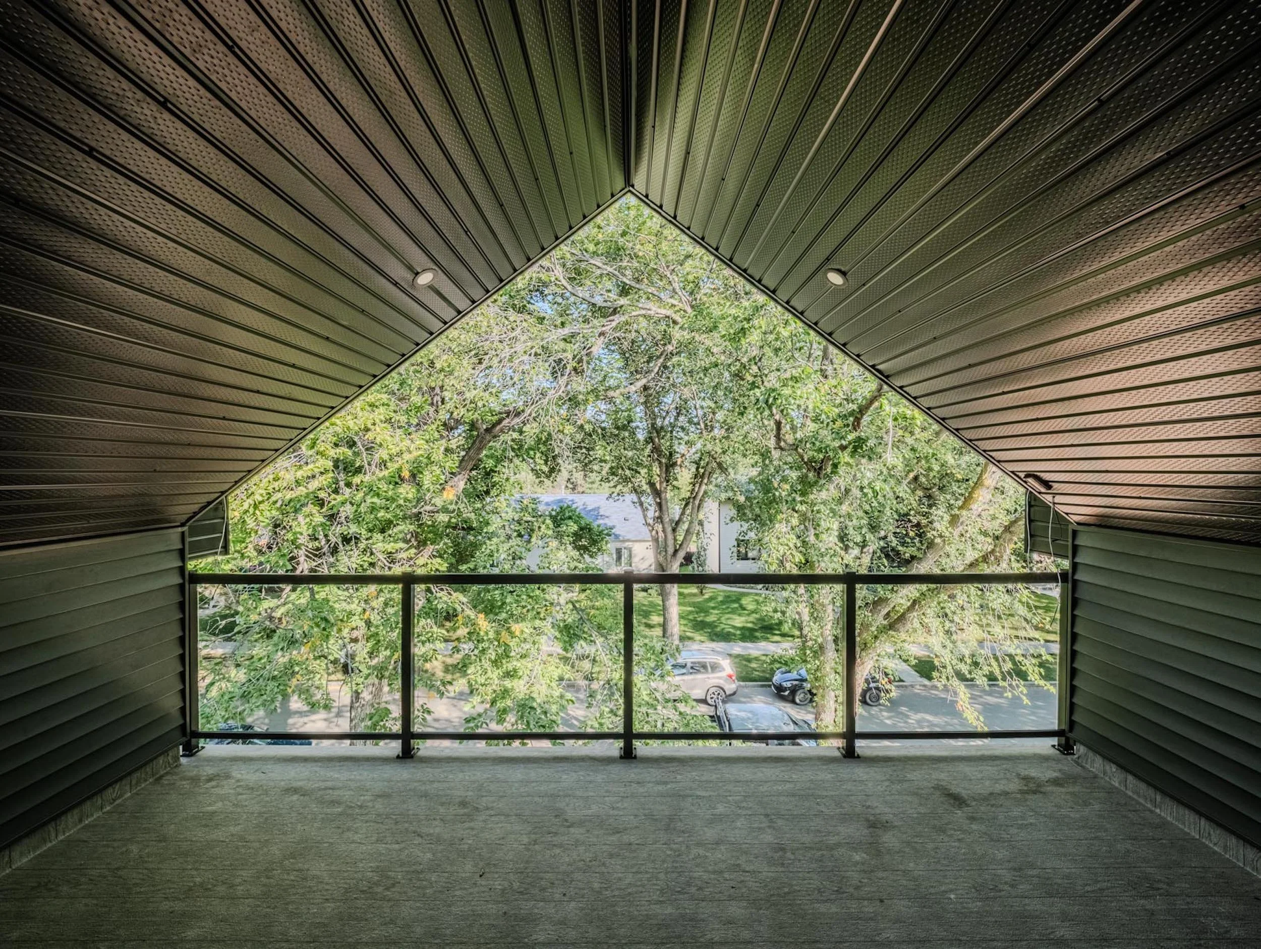 Vaulted third-story balcony view by Omni Homes, looking out into the Belgravia neighborhood tree canopy.