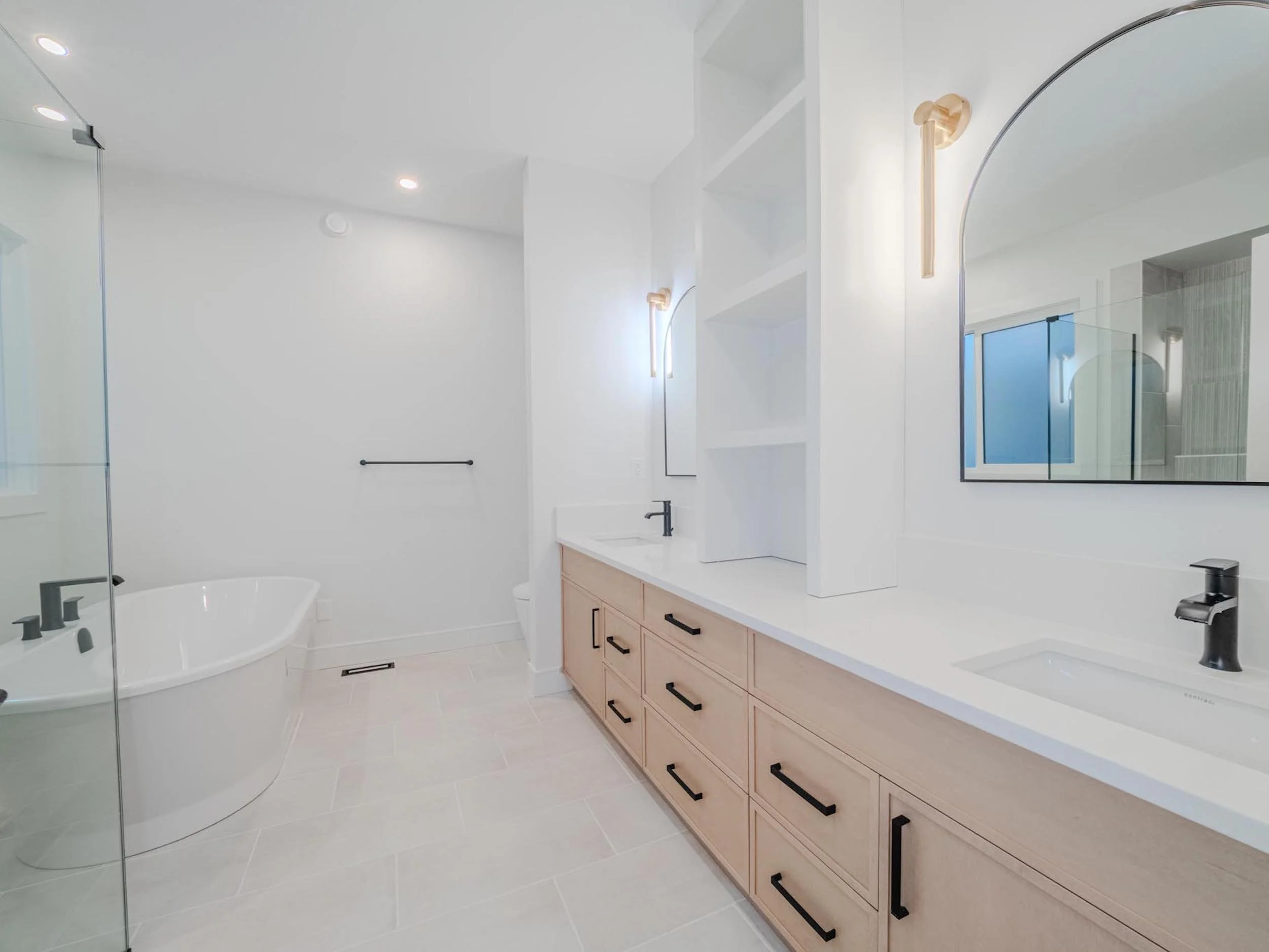 Luxury primary ensuite with custom light oak vanity and modern gold wall sconces in a Belgravia custom build.