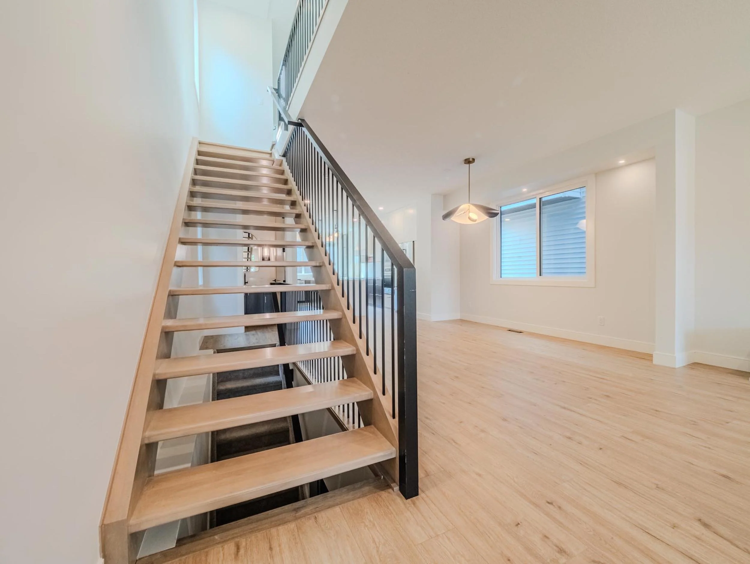 Custom open-riser staircase with wood treads and a modern black metal railing to maximize natural light.