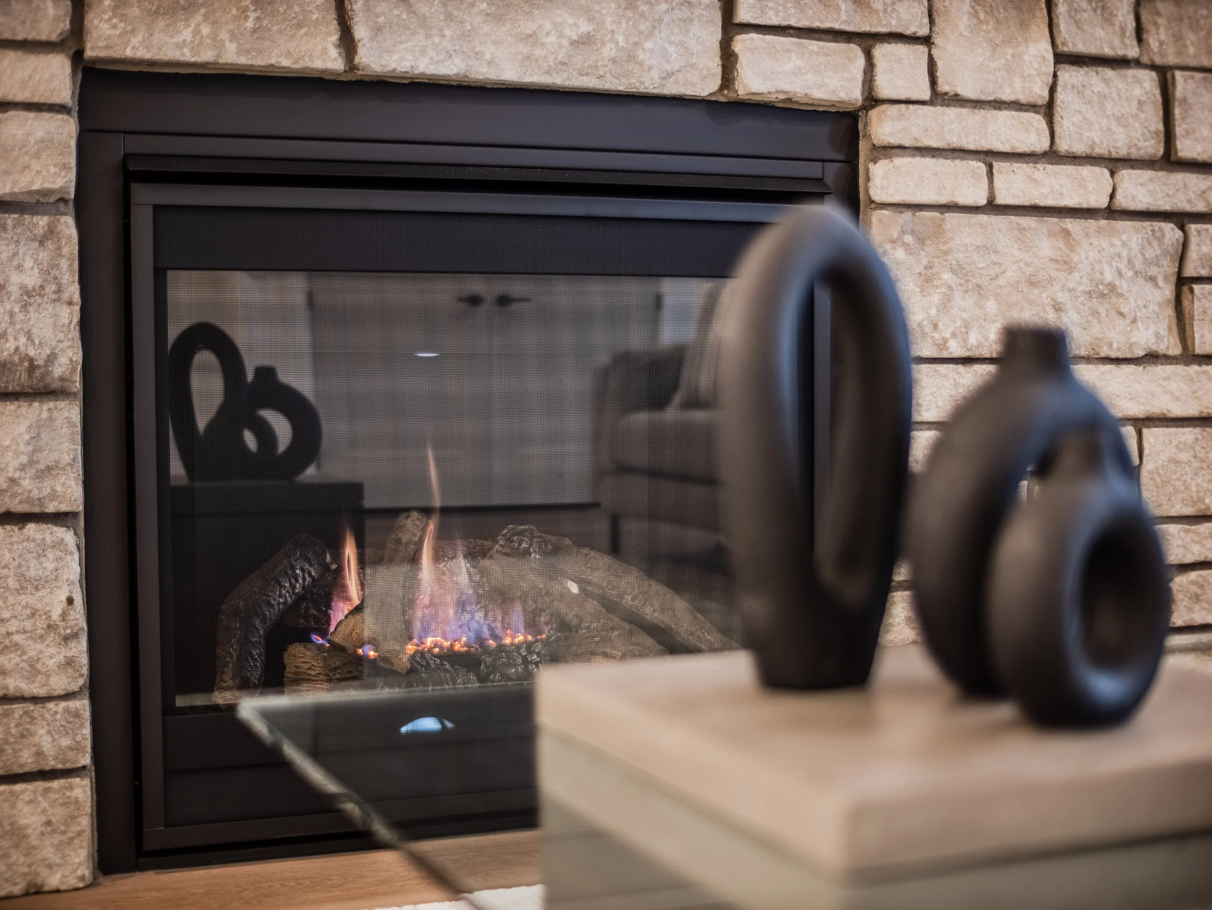 Close-up of natural limestone fireplace with a hand-crafted stone mantle and modern decor accents.