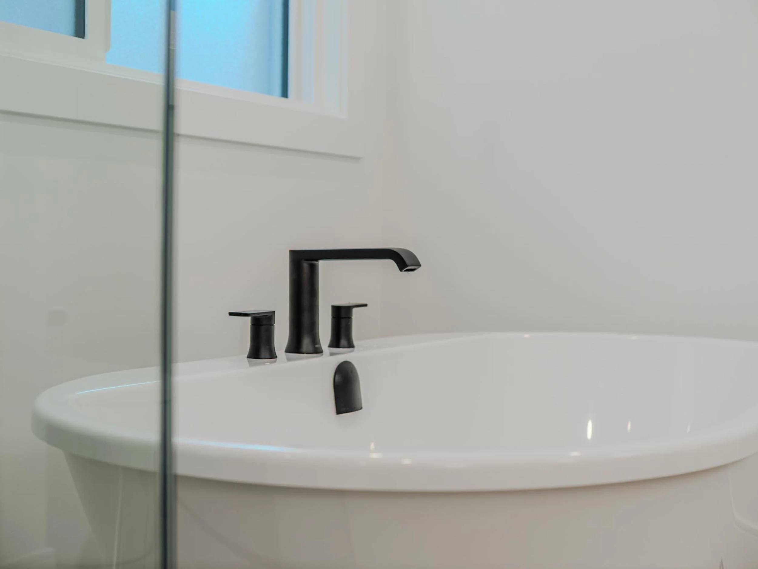 Deep soaking freestanding tub with matte black fixtures, balancing high design with relaxation.