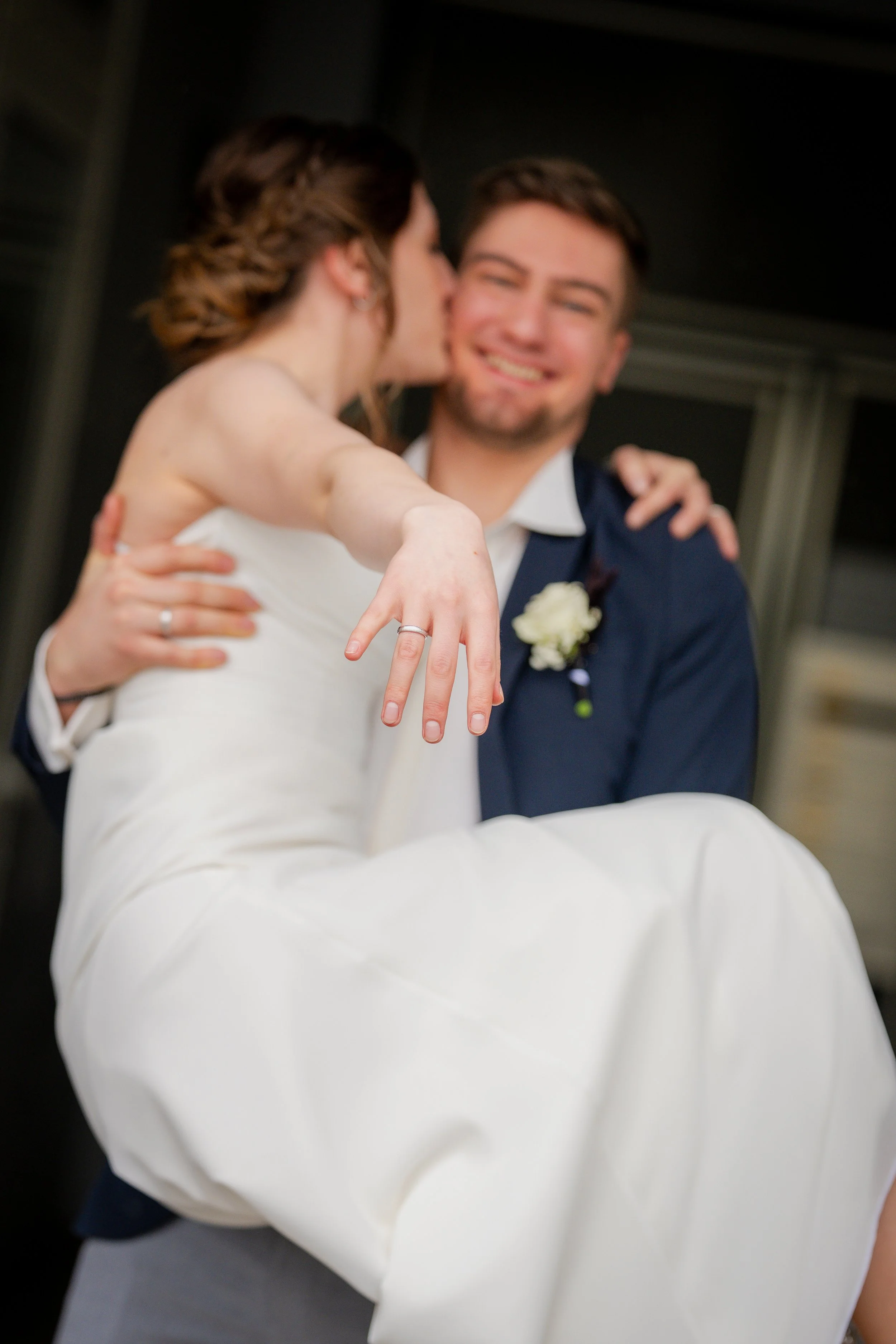 A bride and groom celebrating their wedding, with the bride showing her wedding ring and the groom smiling in the background.