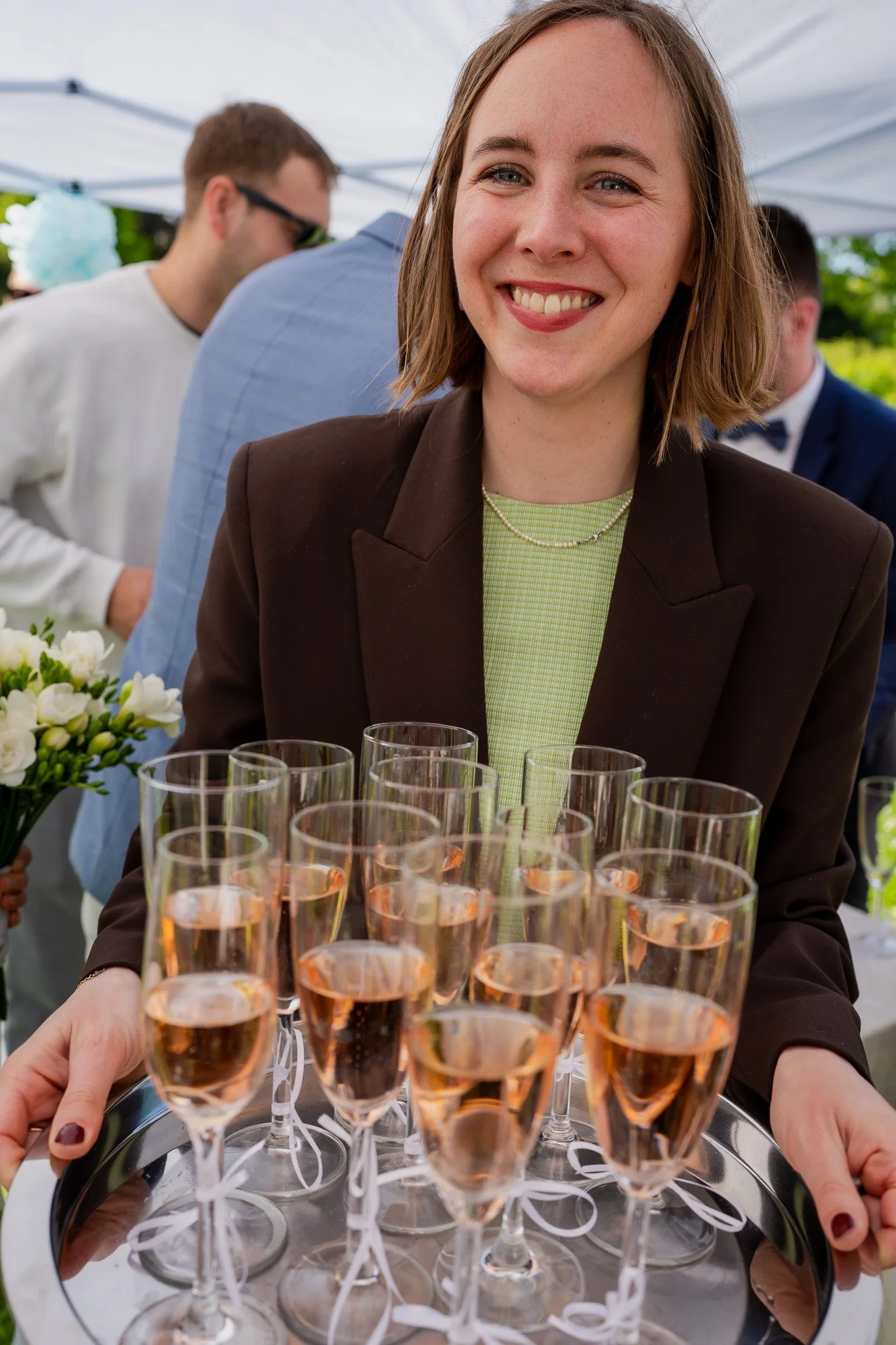 Nahaufnahme eines Lächelnden Frauen in einem Business-Anzug, die auf einer Party oder bei einer Feier Champagner serviert.
