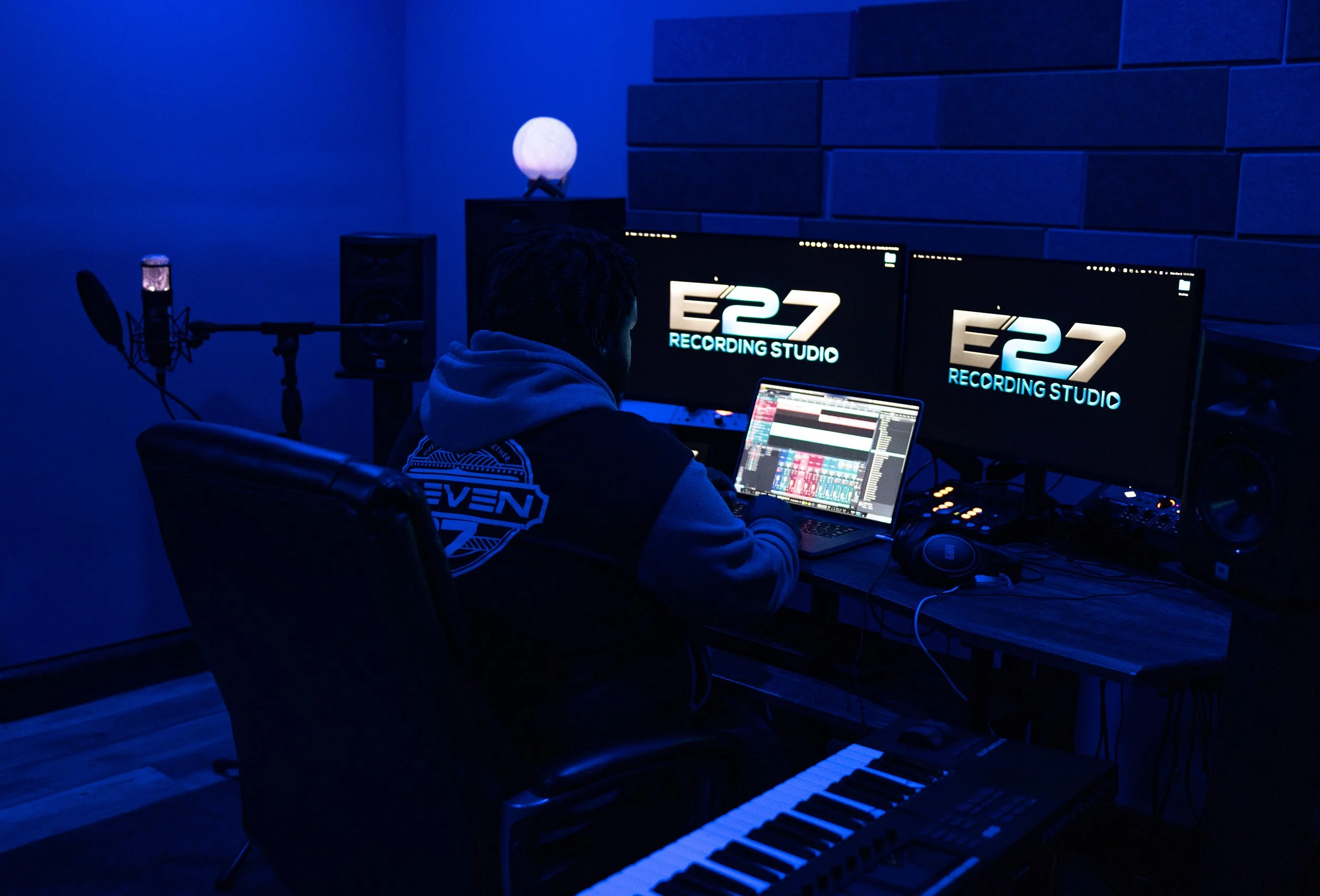 Modern wooden house located in a mountainous area with grass and shrubs in the foreground. Mountains in the background.