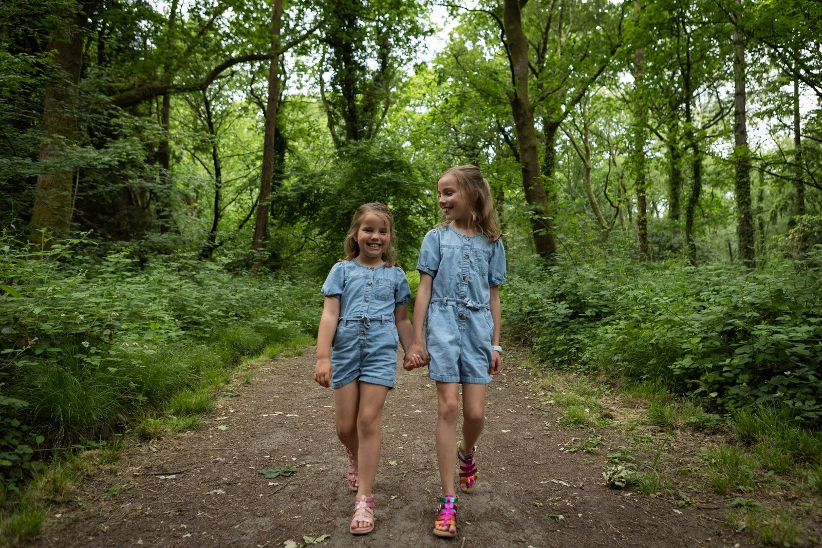 sisters walk through a park down a path hand in hand in Summer time