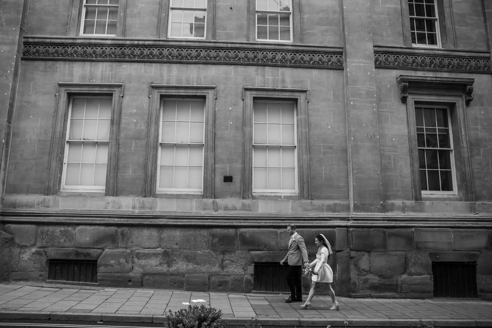 bride and groom walk through Bath City Centre
