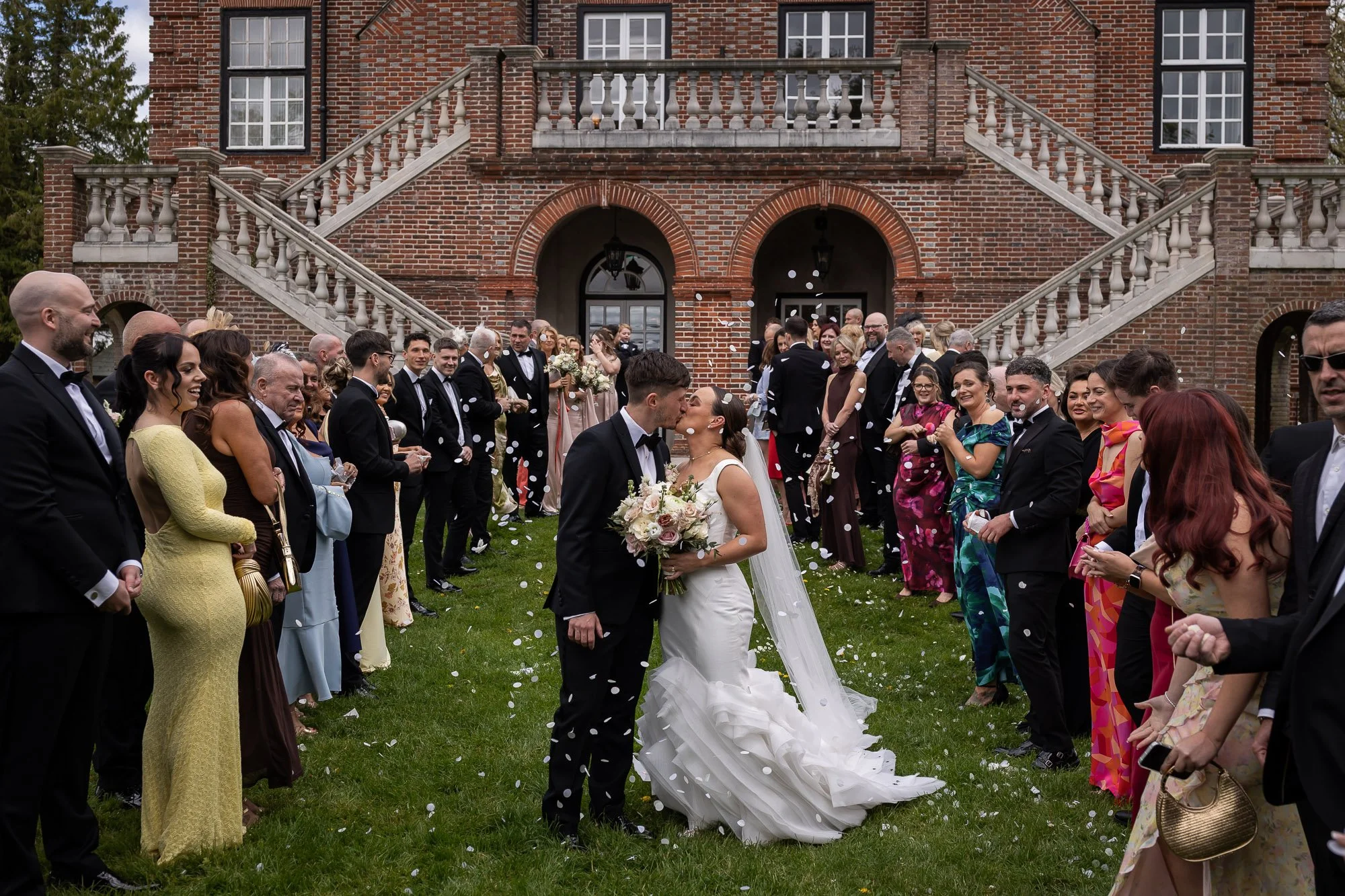 confetti thrown whilst bride and groom kiss