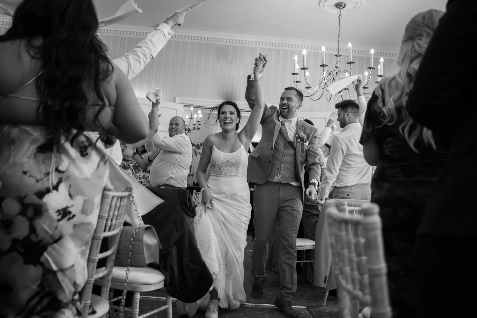 bride and groom entering wedding breakfast excitedly to guests cheering