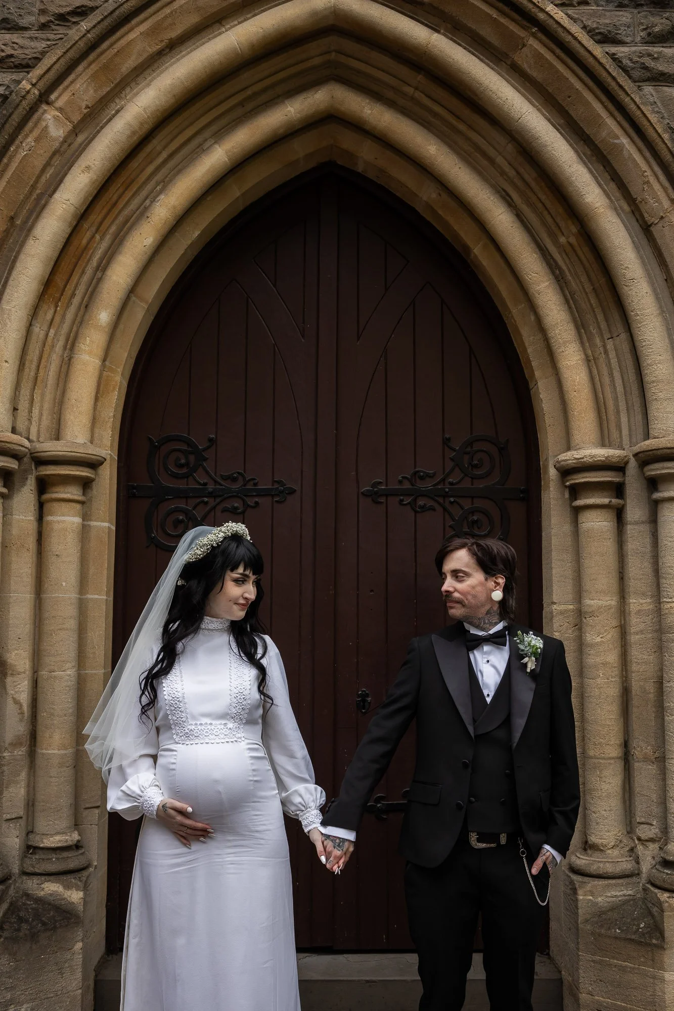 pregnant bride poses for photograph with husband