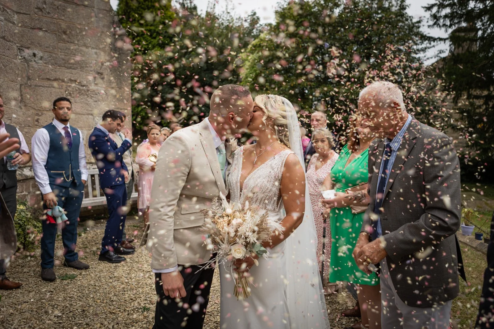 colourful confetti surrounds bride and groom as they kiss