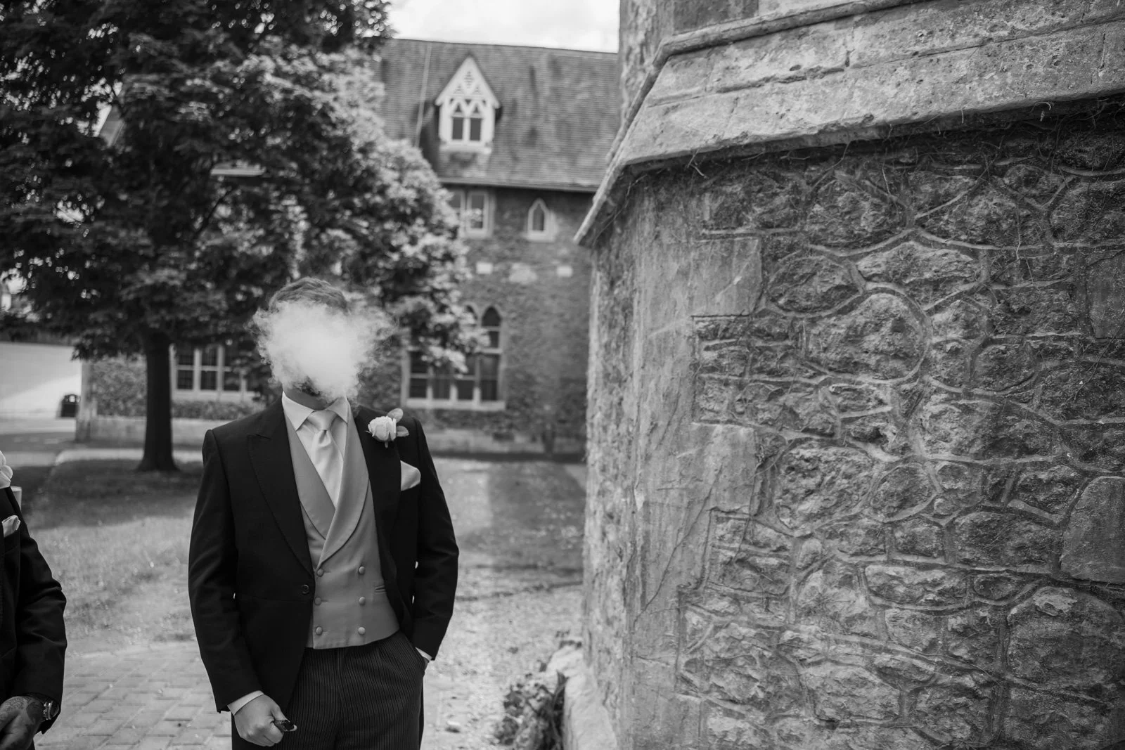 a cloud of vapour from a vape covers the face of groomsman
