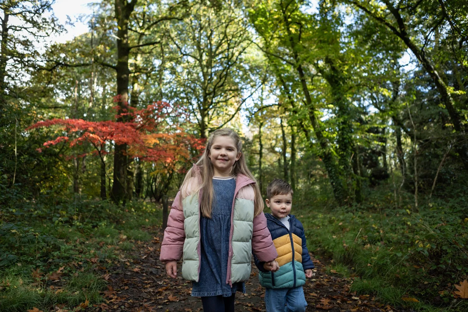 brother and sister smile whilst walking and holding hands