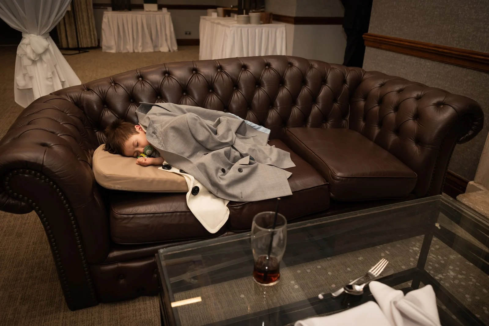 little boy sleeps under coat during wedding party