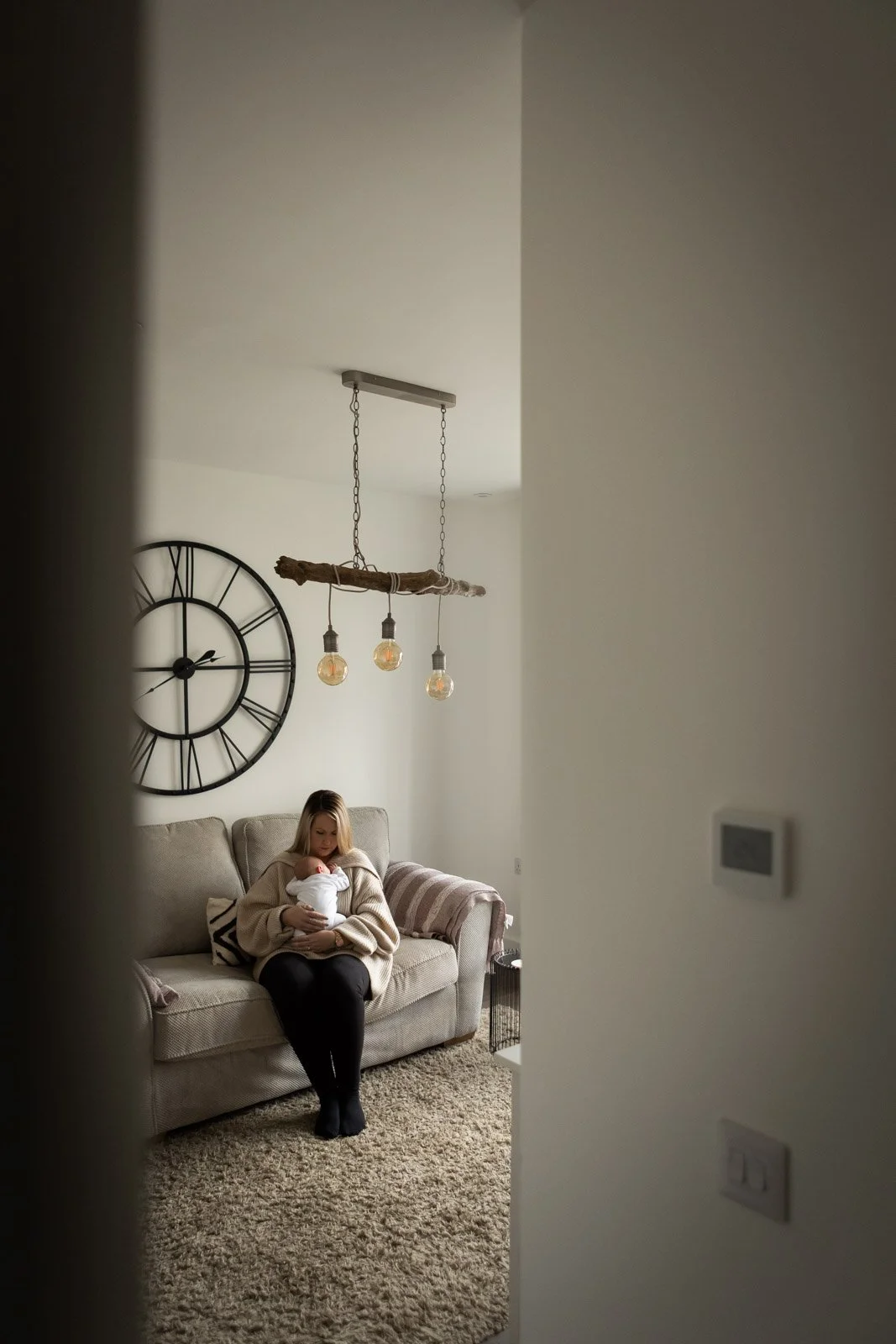 mother seen through doorway in living room holding baby on couch