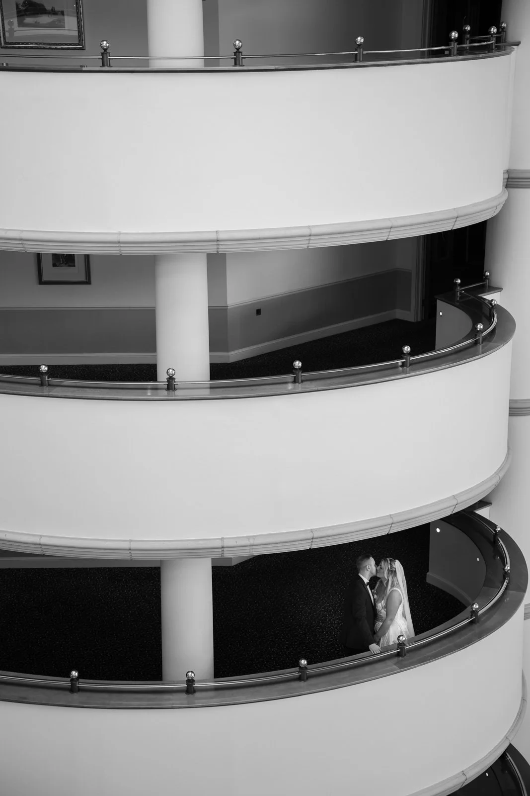 Celtic Manor wedding venue foyer. Newly married couple hold each other on a floor of the hotel