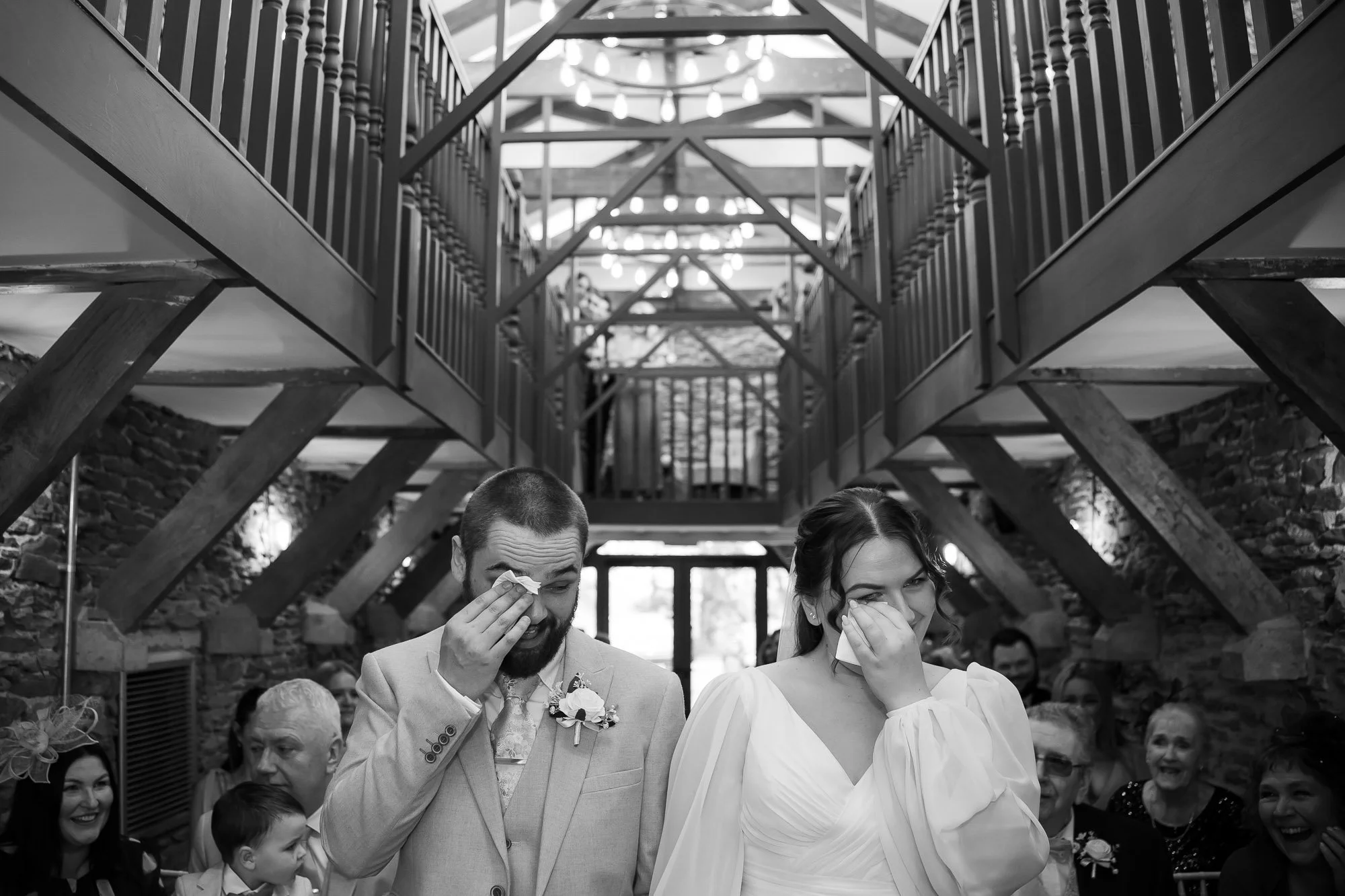 bride and groom wipe tears simultaneously during ceremony