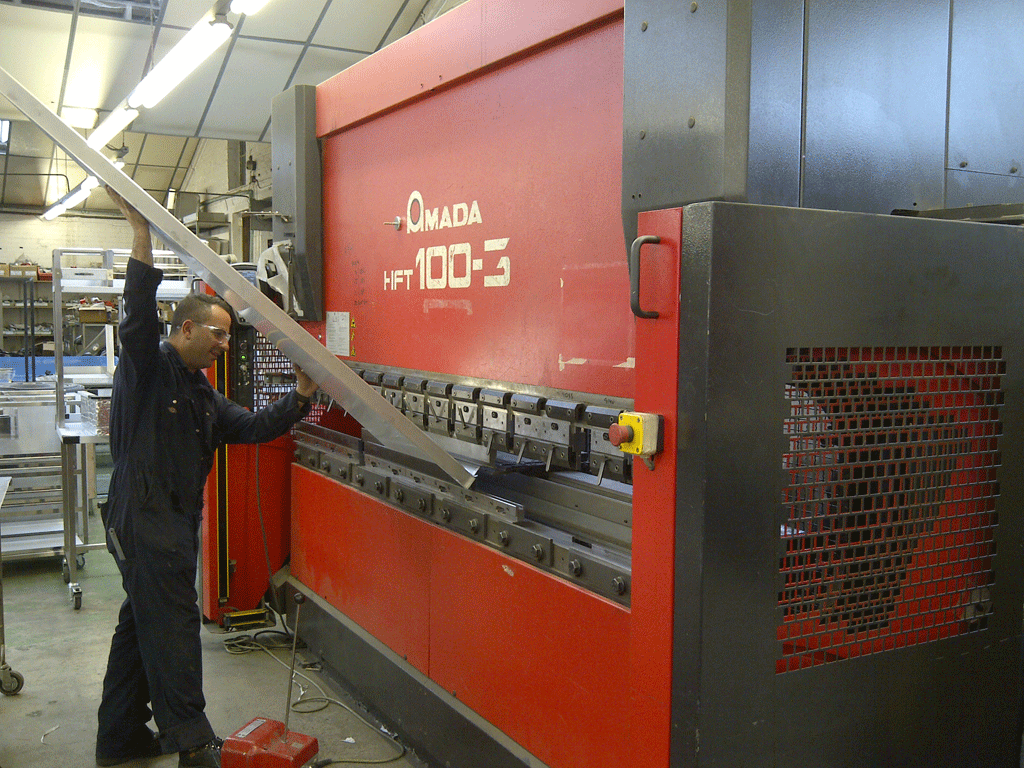 Man operating Amada press brake machine in a workshop