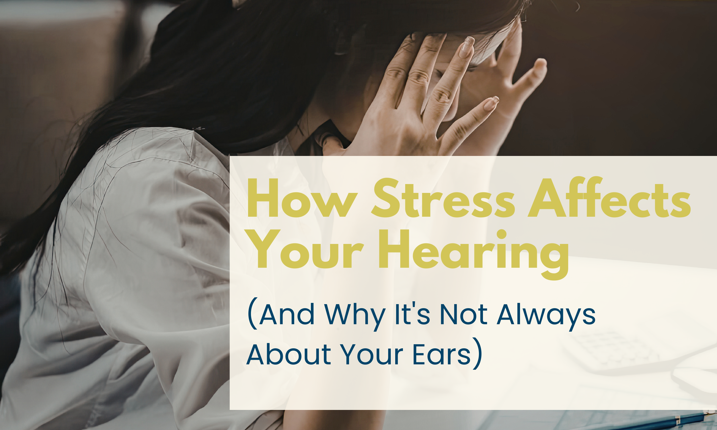 Woman with head in hands at a desk, overlaid with the blog title: How Stress Affects Your Hearing (And Why It's Not Always About Your Ears)