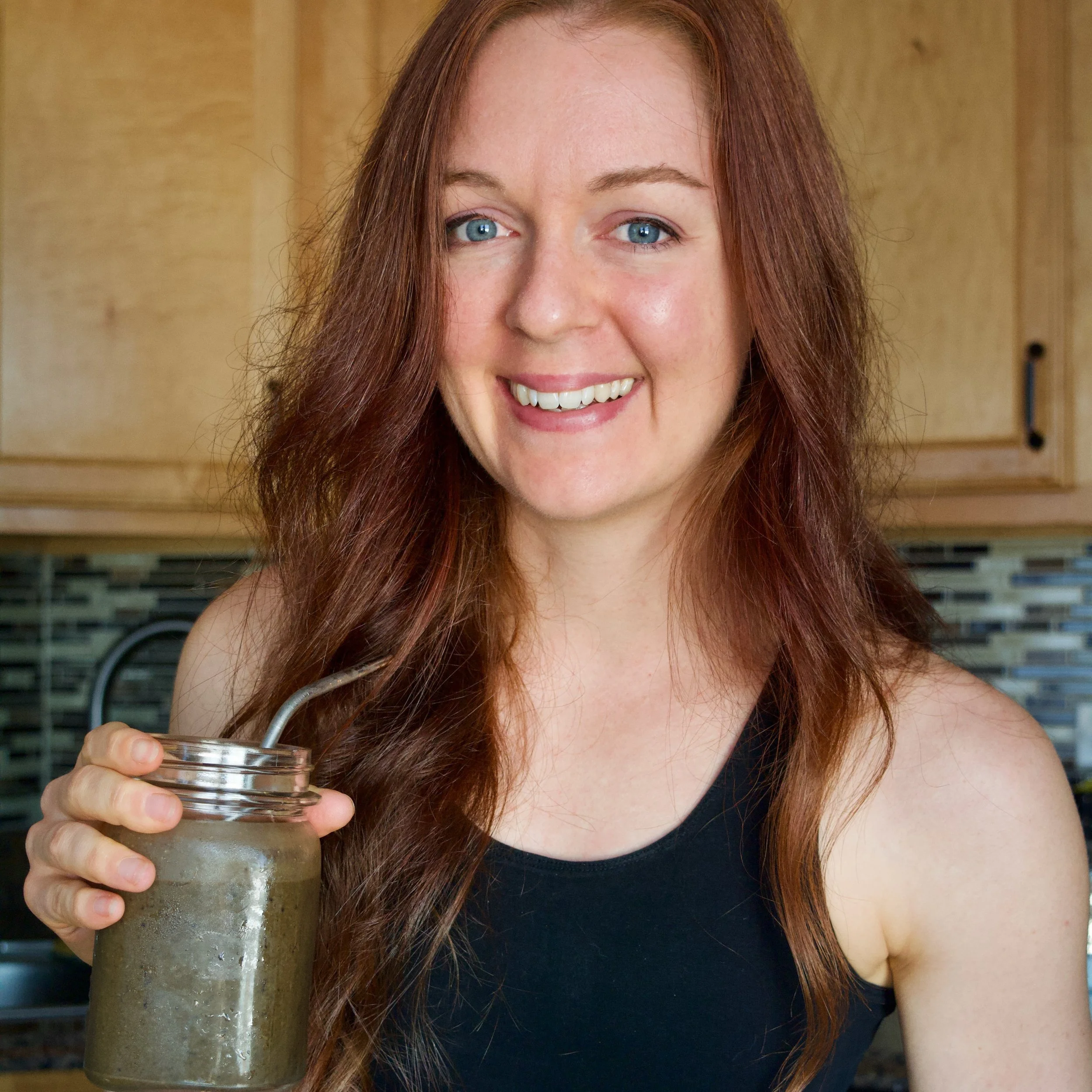 Lucia stands in her kitchen holding her favorite post workout superfood shake smiling at the camera