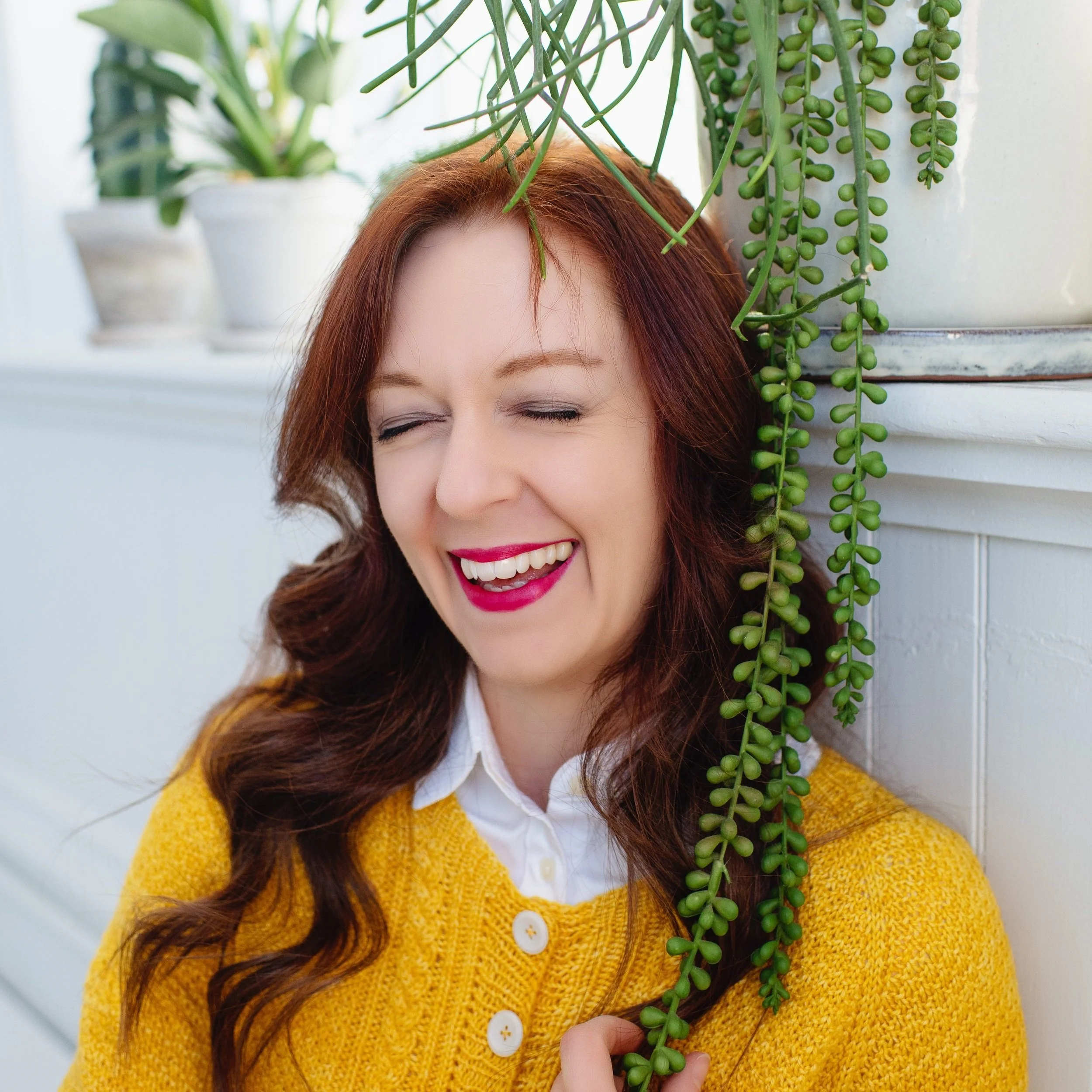 Lucia sits on the floor by a window with plants