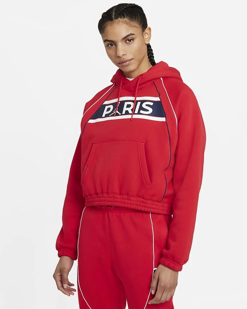 A young woman with braided hair wearing a red hooded sweatshirt and matching red sweatpants, with the word 'Paris' on the sweatshirt.
