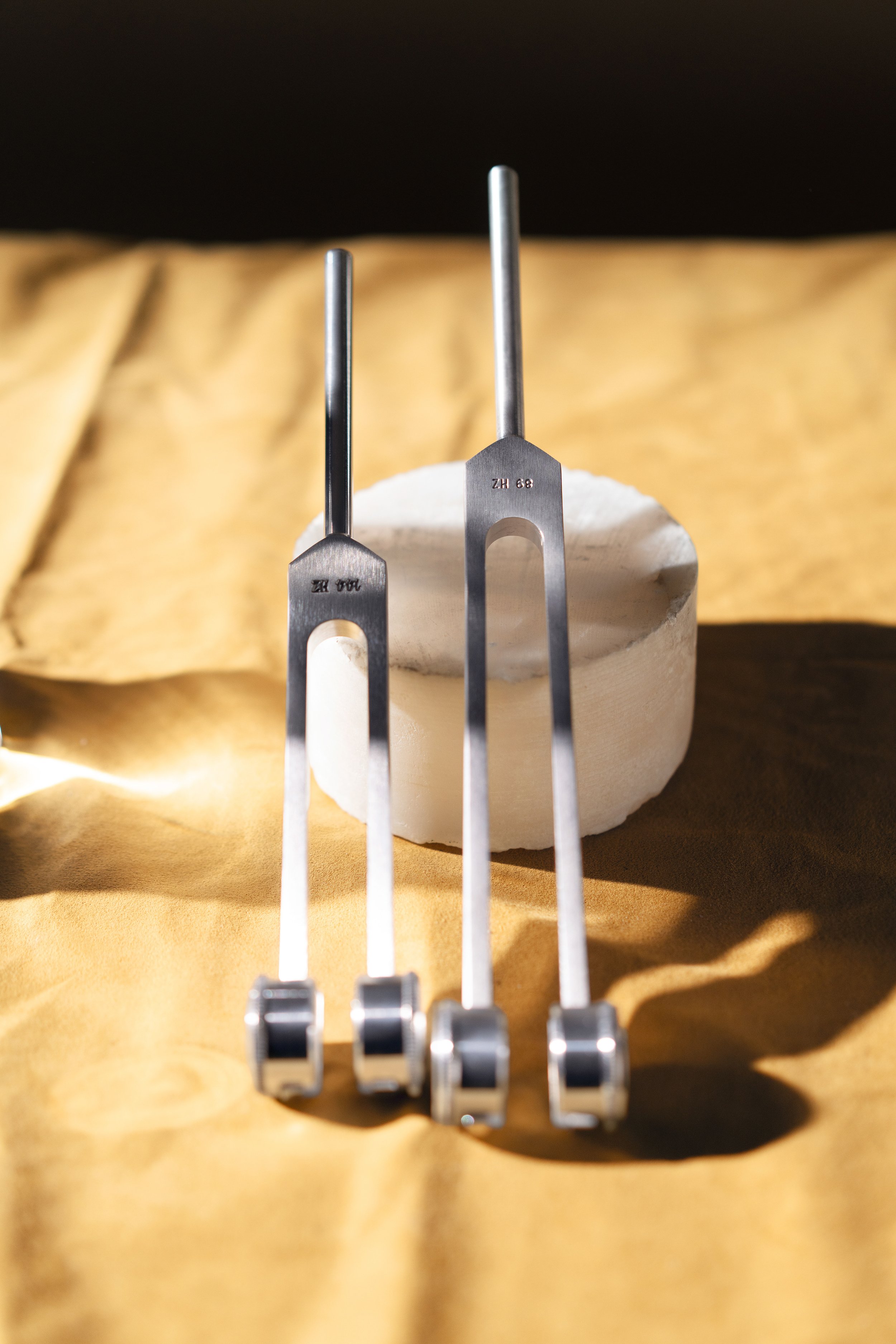 Biofield Tuning forks resting on stone and textured yellow background