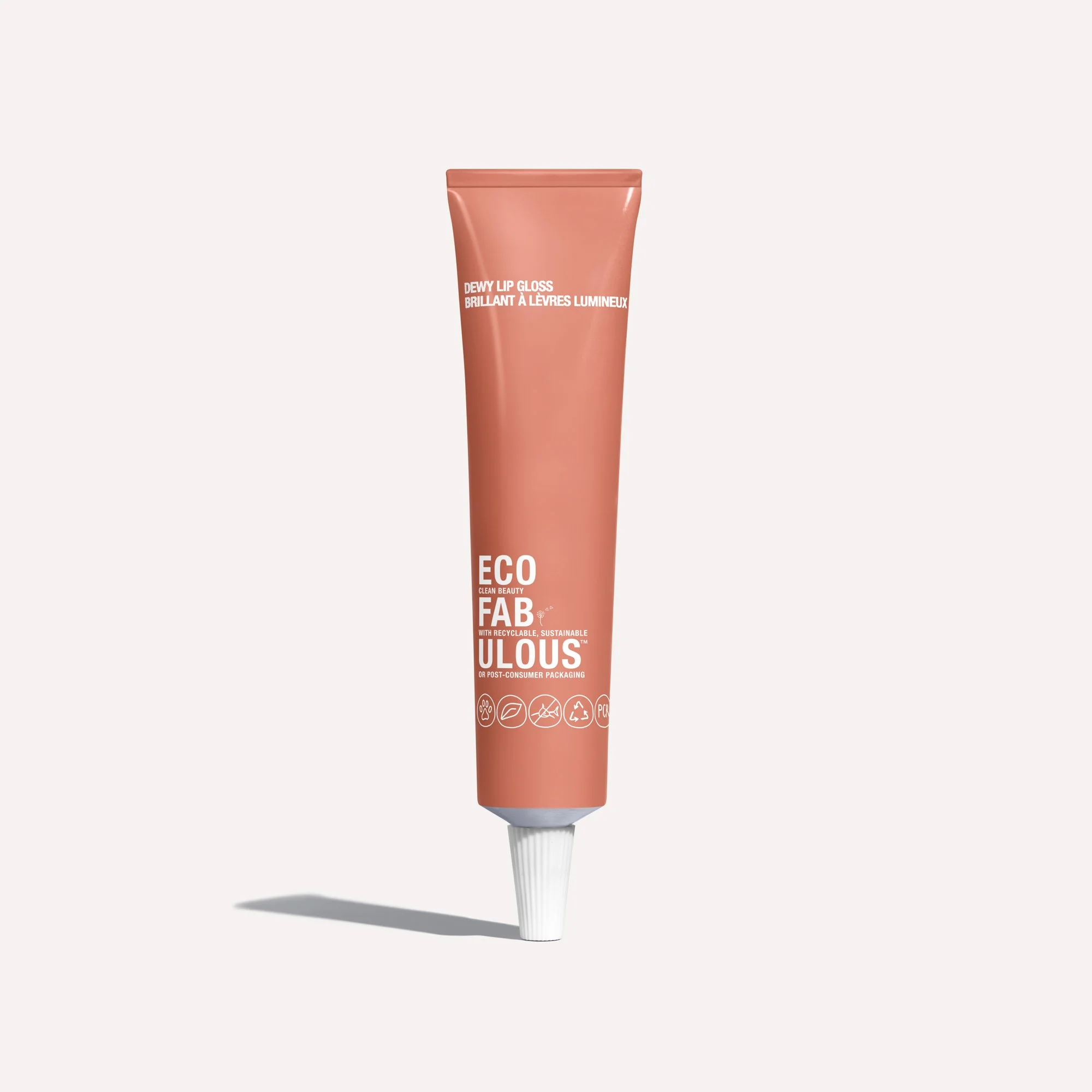 A peach-colored tube of Eco Fabulous Dewy Lip Gloss with a white cap on a plain white background, casting a shadow.
