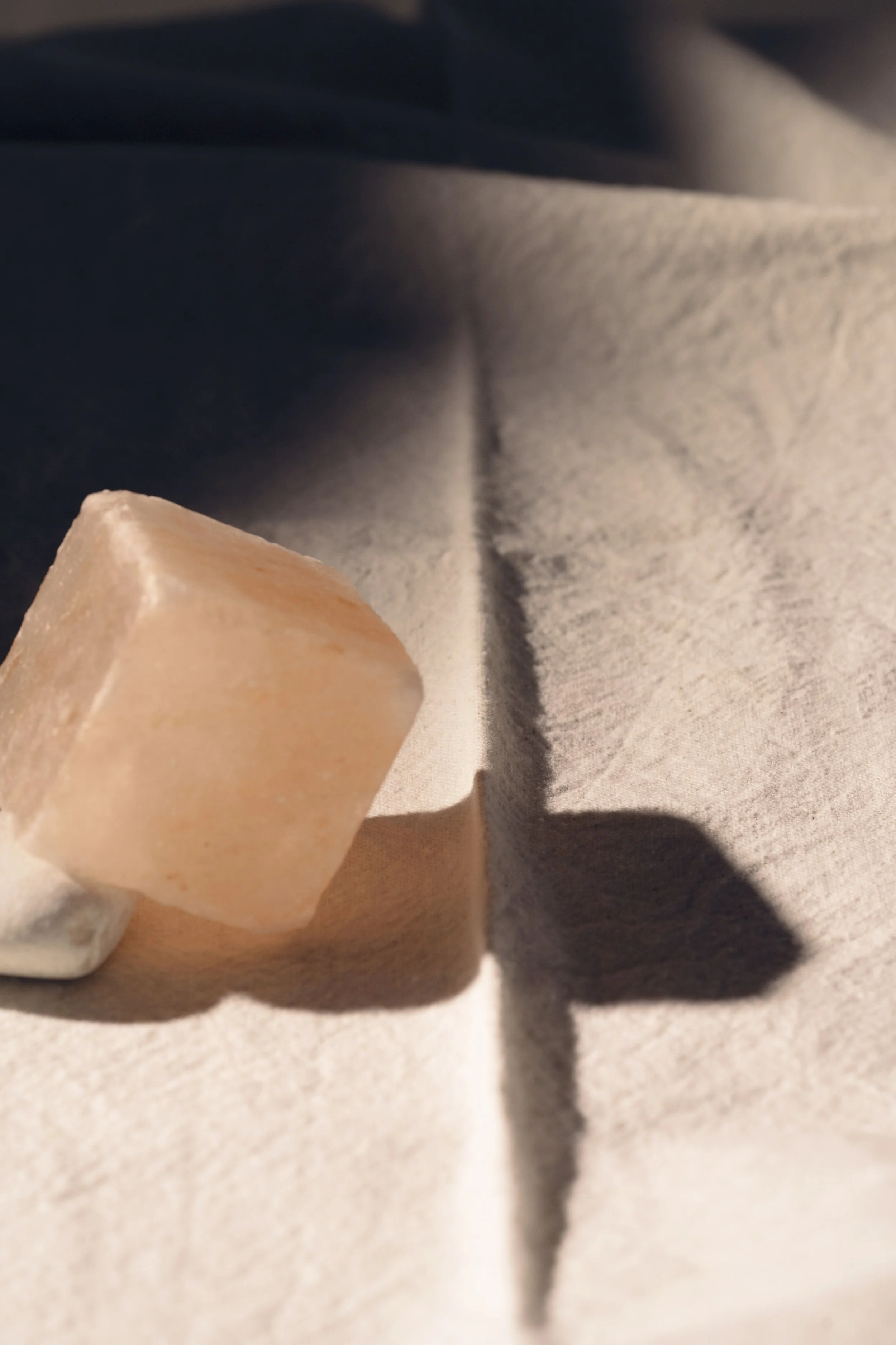 A small salt rock placed on a light-colored cloth, casting a shadow on the fabric.